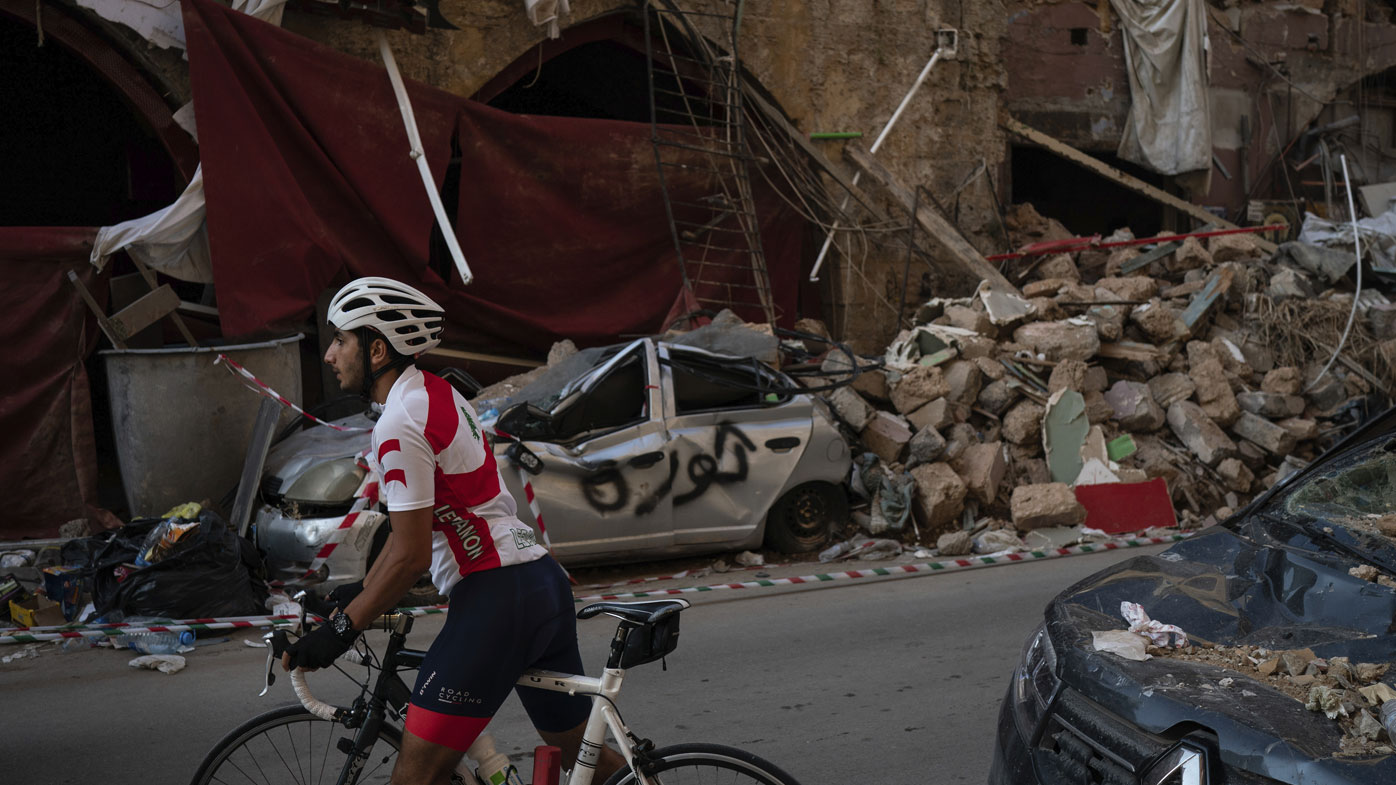 A cyclist rides past destroyed buildings and cars in a neighbourhood near the site of last week's explosion that hit the seaport of Beirut, Lebanon, Tuesday, Aug. 11, 2020