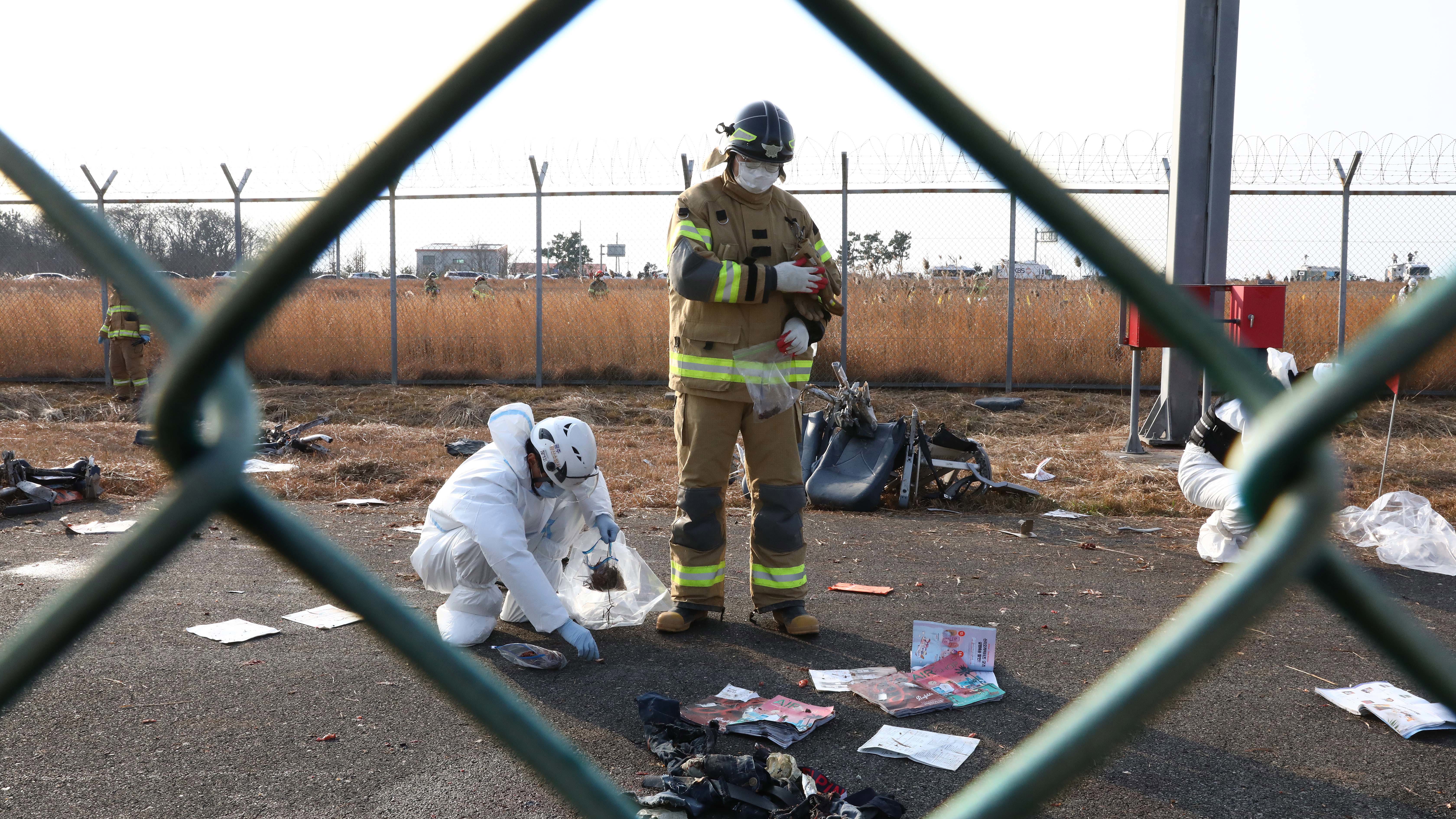 Rescue team members check the wreckage of the crashed plane in South Korea.