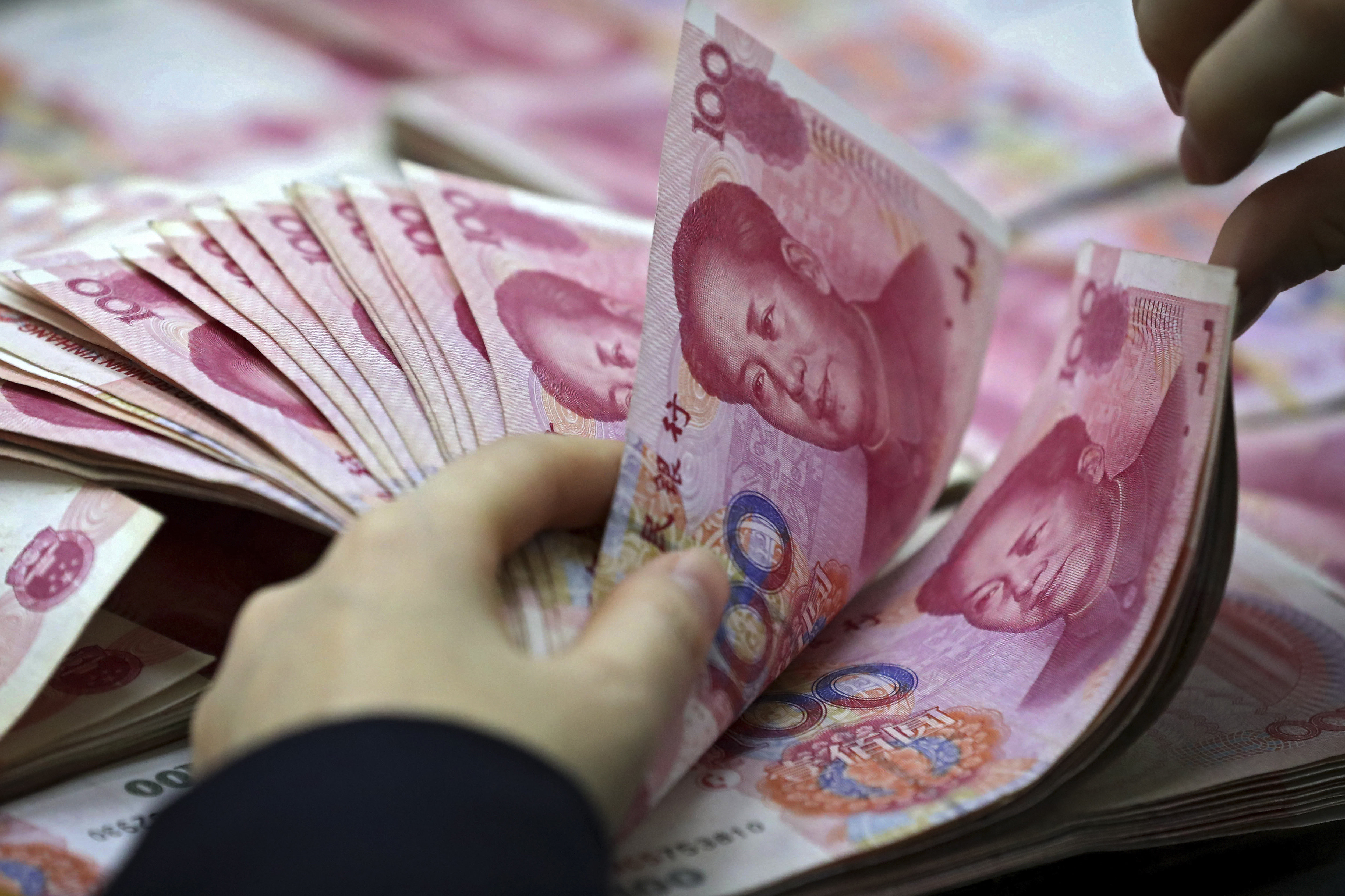 A clerk counts Chinese currency notes