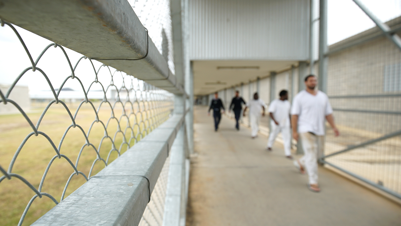 Staff escort prisoners through a prison in Australia.