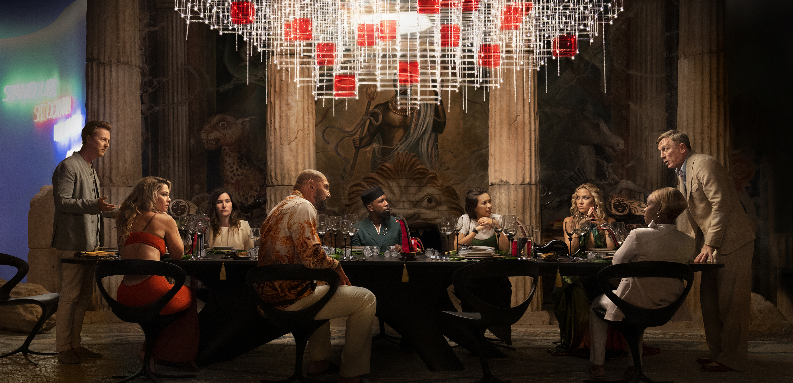 A  scene from "Glass Onion: A Knives Out Mystery" featuring (L-R) Edward Norton, Madelyn Cline, Kathryn Hahn, Dave Bautista, Leslie Odom Jr., Jessica Henwick, Kate Hudson, Janelle Monae, and Daniel Craig.