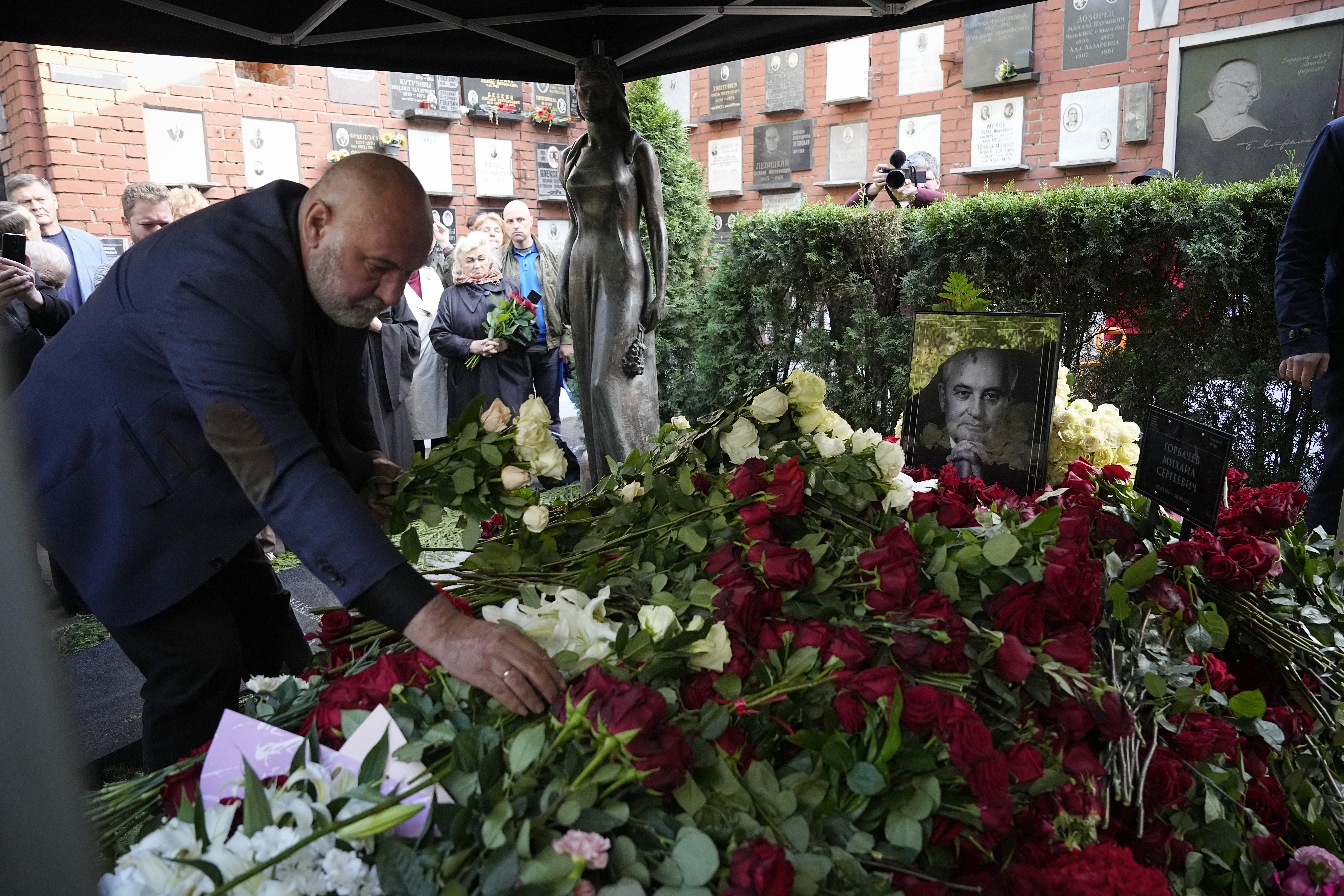 People lay flowers to the grave of former Soviet President Mikhail Gorbachev during his funeral at Novodevichy Cemetery in Moscow, Russia, Saturday, Sept. 3, 2022 