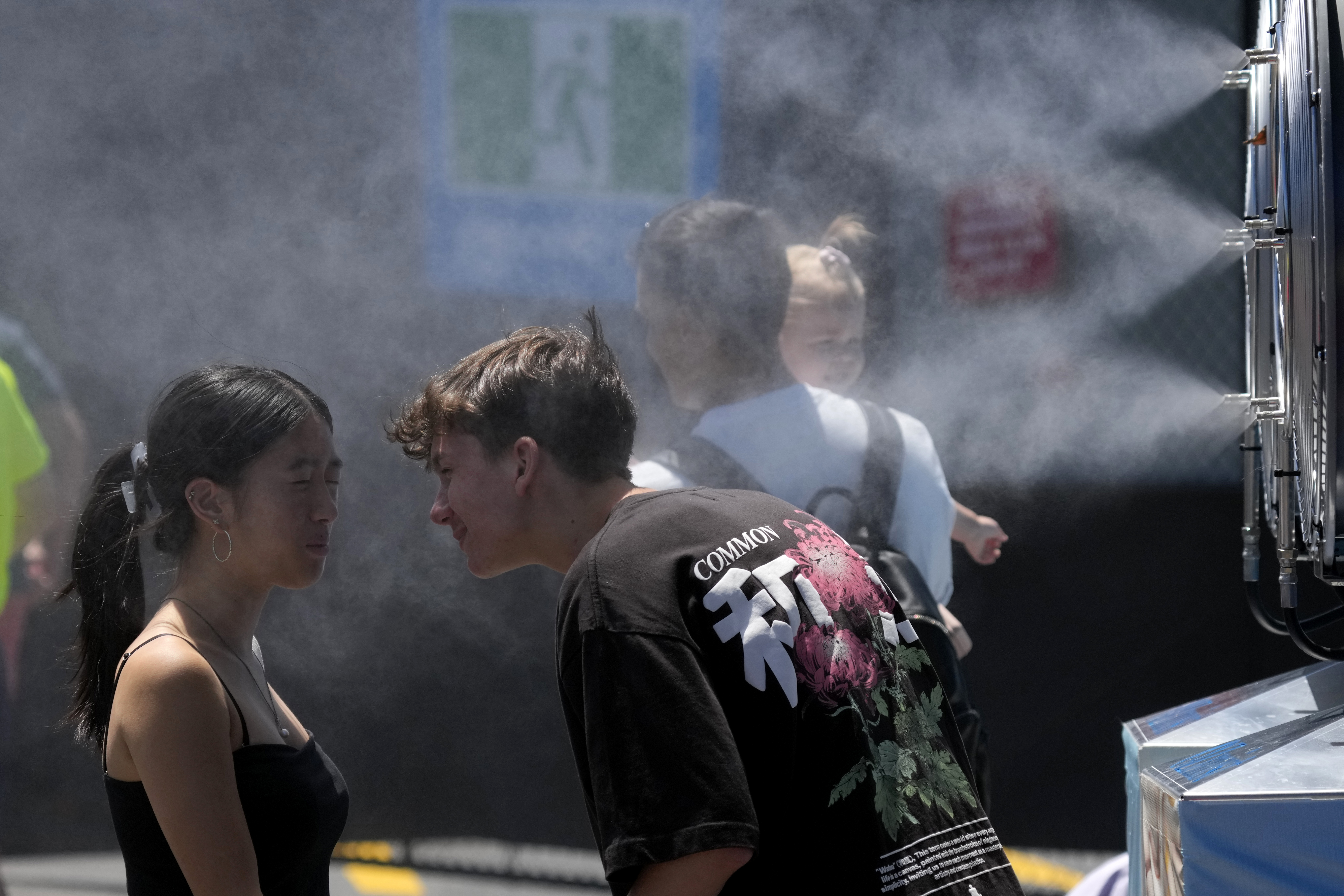 Fans cool down at a water mister machine at Melbourne Park.