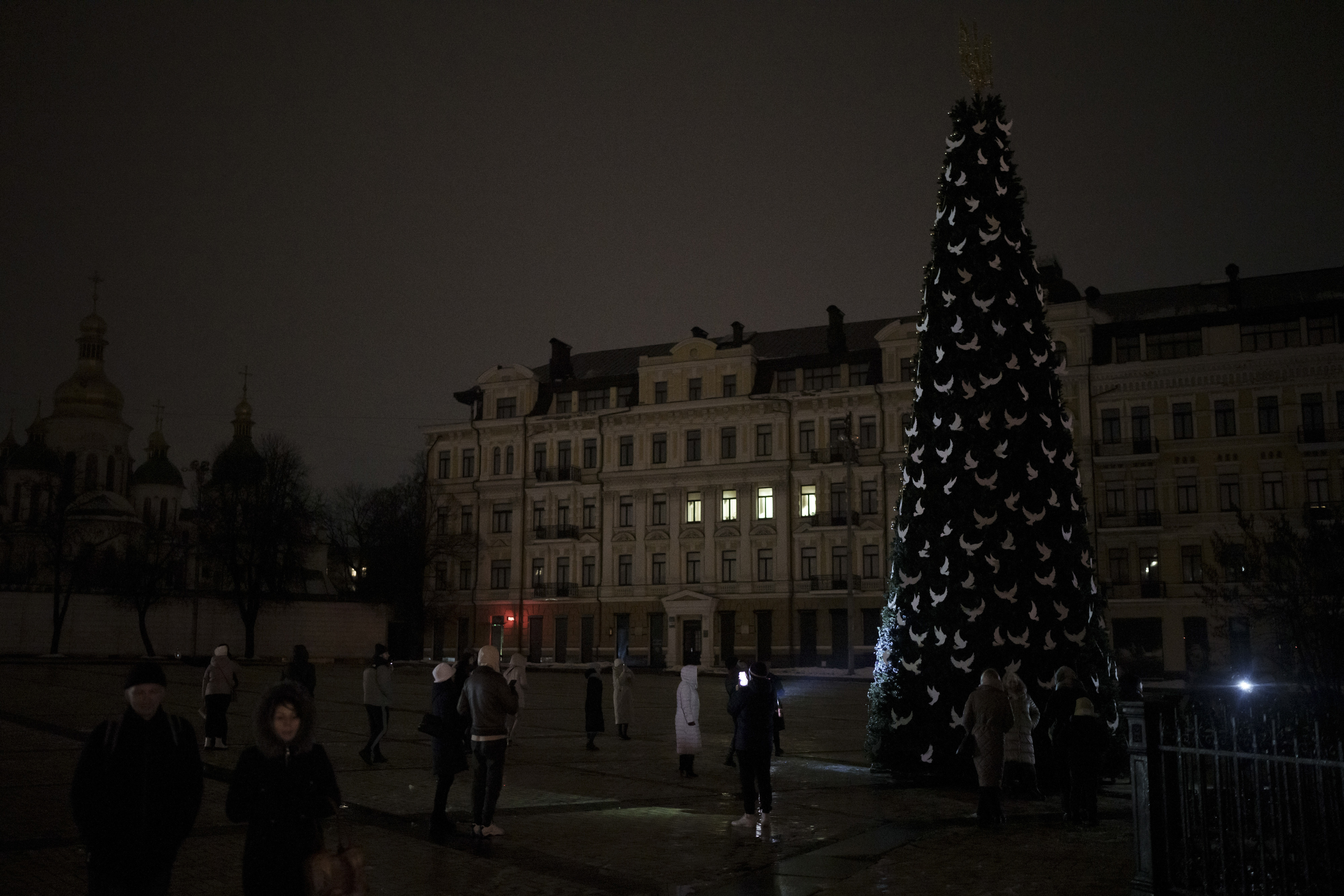 Ukrainians take photos of a newly built Christmas tree at Sophia square as partial power outages continue in Kyiv, Ukraine, Saturday, Dec. 17, 2022.  