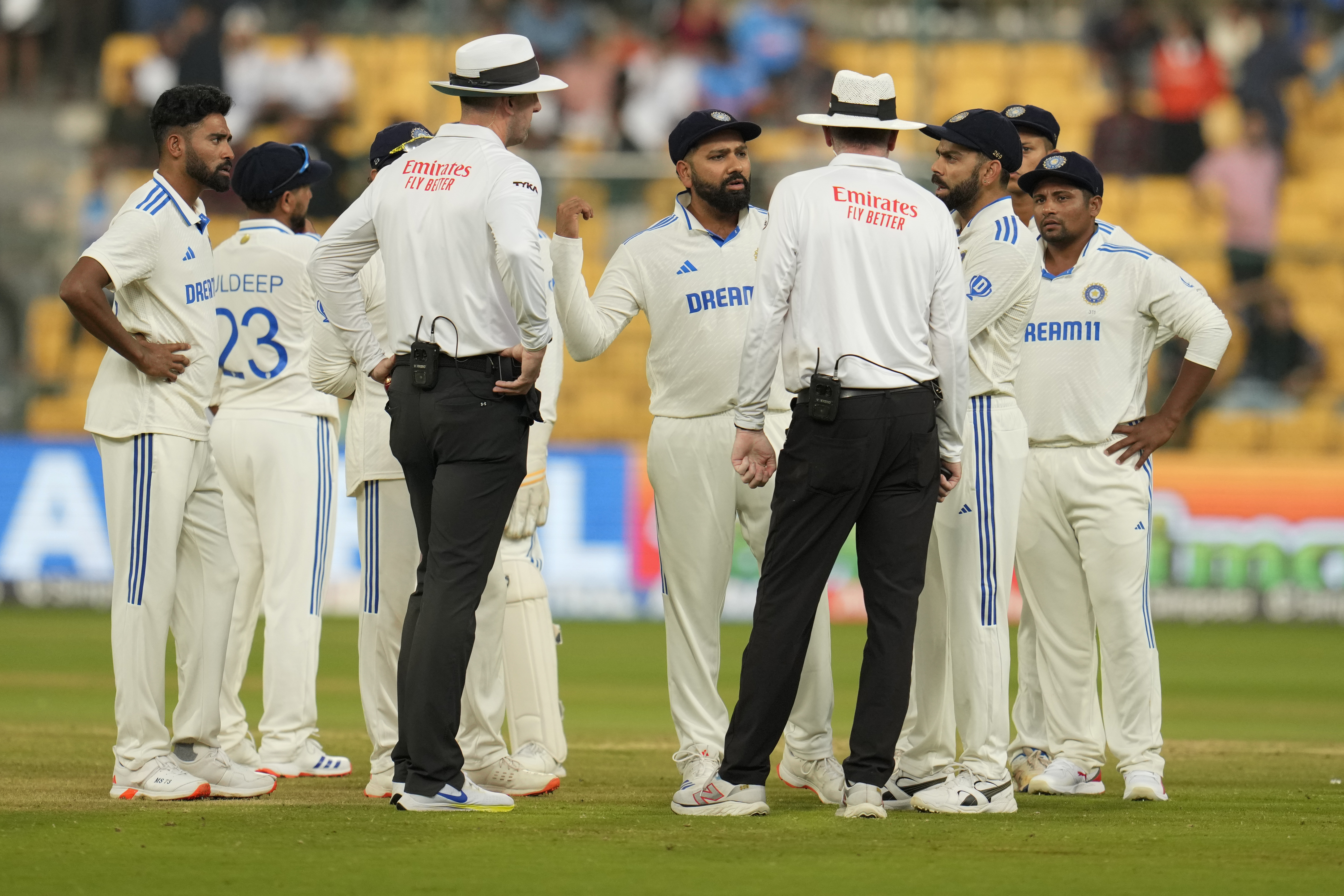 India's captain Rohit Sharma, center, speaks to the umpires after bad light stopped play on the day four of the first cricket test match between India and New Zealand at the M.Chinnaswamy Stadium, in Bengaluru, India, Saturday, Oct. 19, 2024. (AP Photo/Aijaz Rahi)