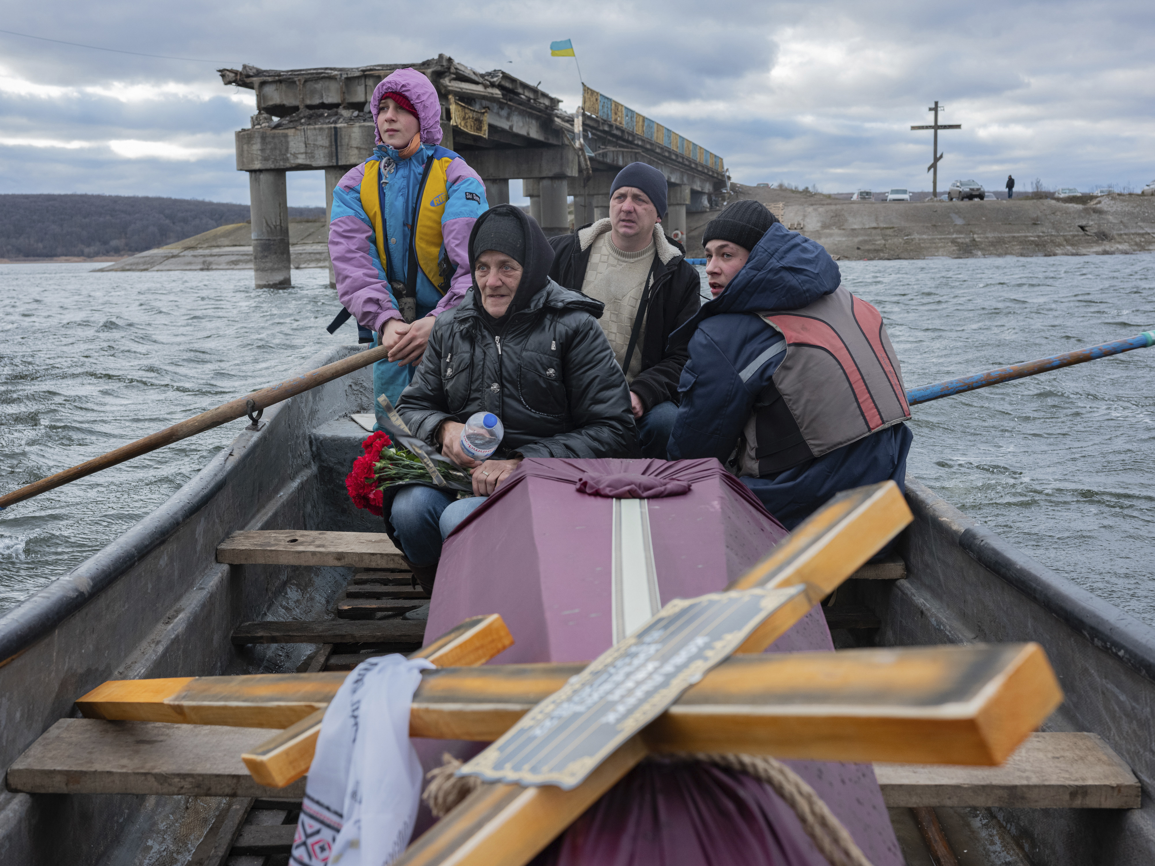 A woman sits in a boat crossing the Siverskyi-Donets river near Staryi-Saltiv, Kharkiv region on Wednesday Jan. 4, 2023, transporting the coffin containing her dead son, a soldier who was killed in fighting with Russians. (AP Photo/Erik Marmor)