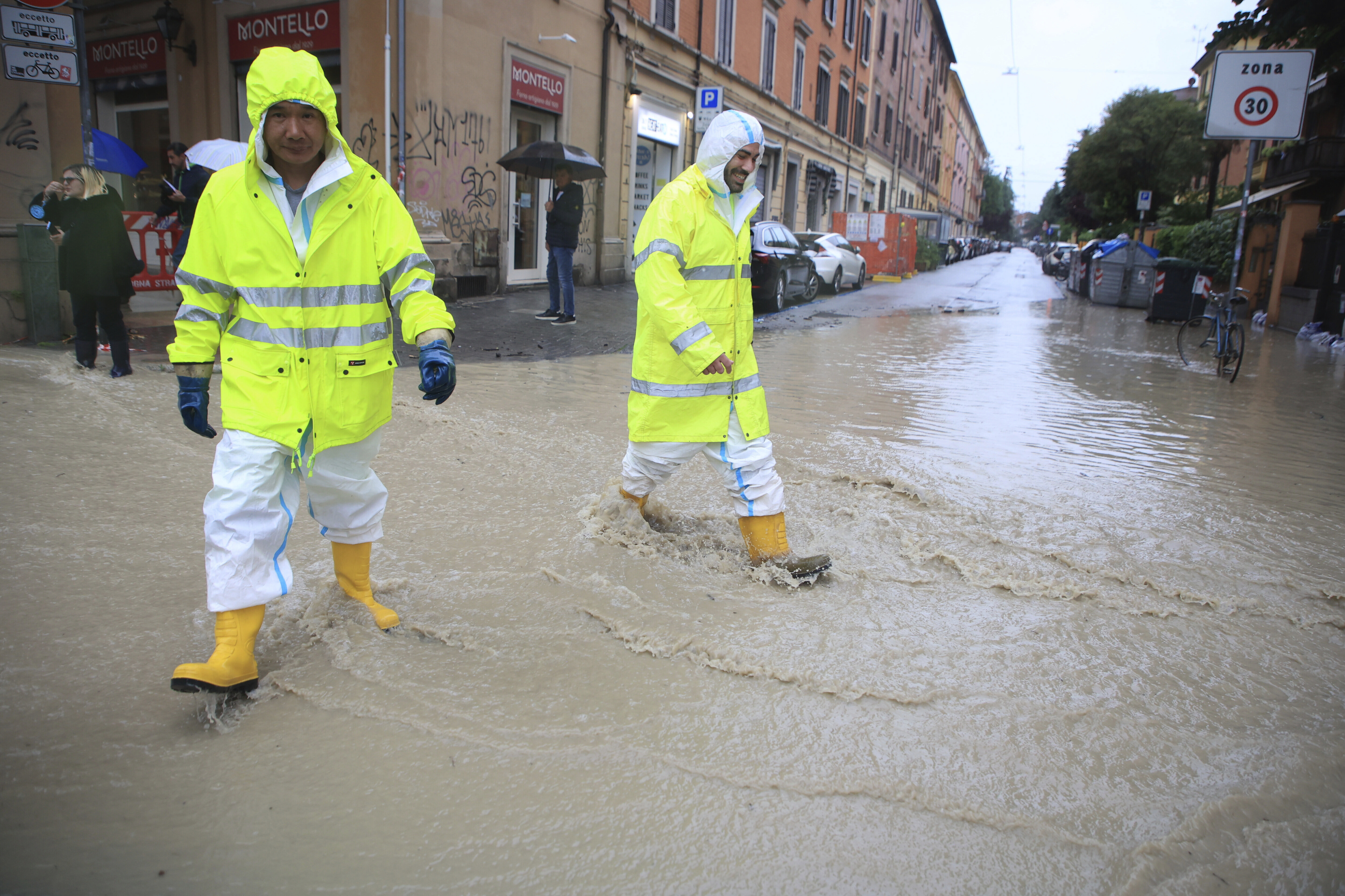 People crosses a flooded street in Bologna, Italy, Tuesday, May 16, 2023.