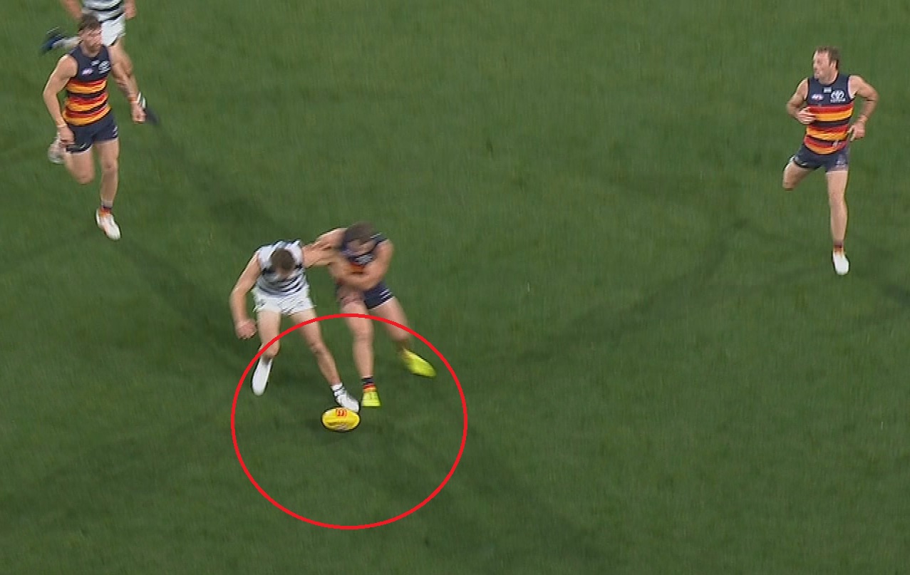 Geelong player Tom Atkins kicks the ball out ahead of Adelaide's Zac Taylor.