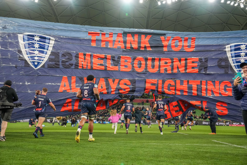 Rebels players run through a banner at AAMI Park.