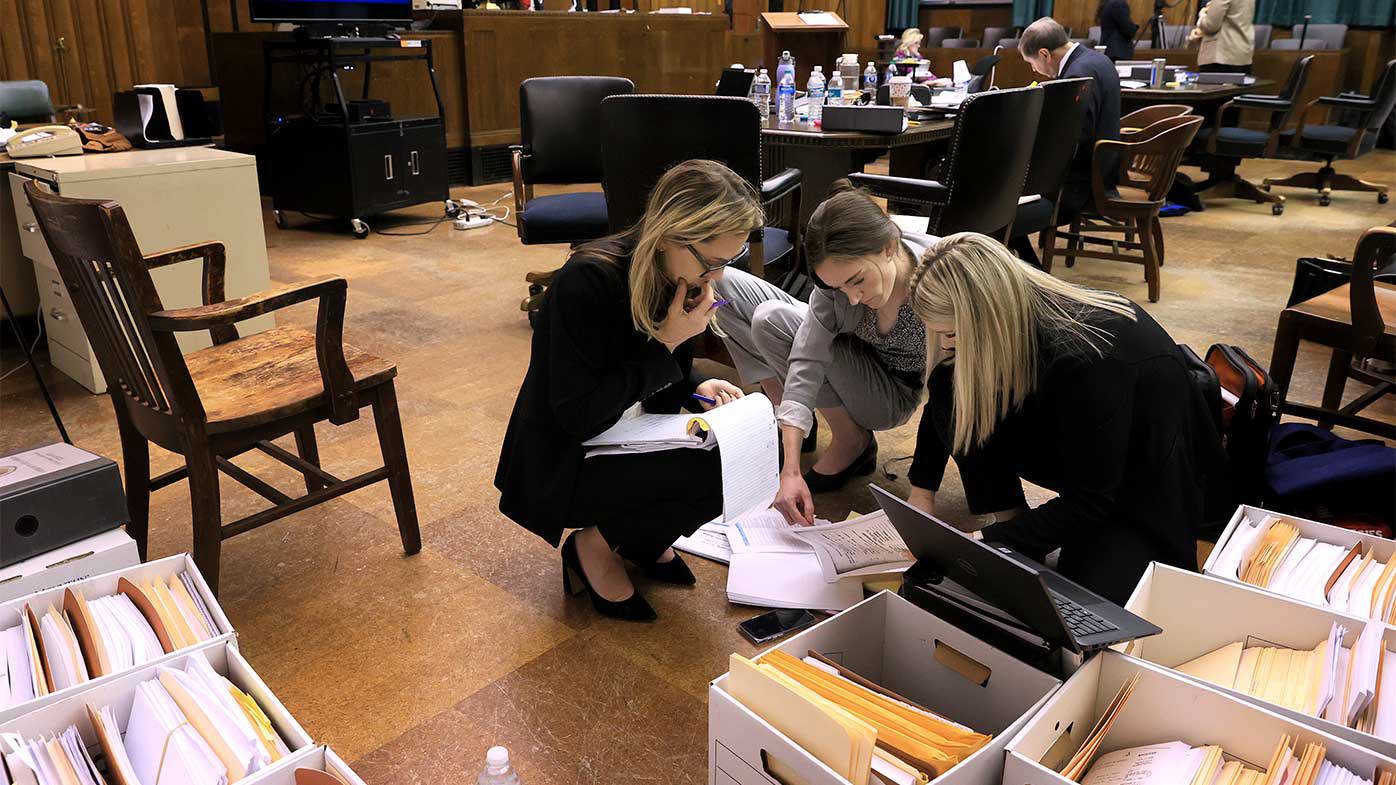 Attorneys Lindsay Runnels and Kylie Mank and paralegal Maci Morgan search through boxes of exhibits before court restarts after a break for lunch during the fourth day of Lamar Johnson's wrongful conviction hearing.