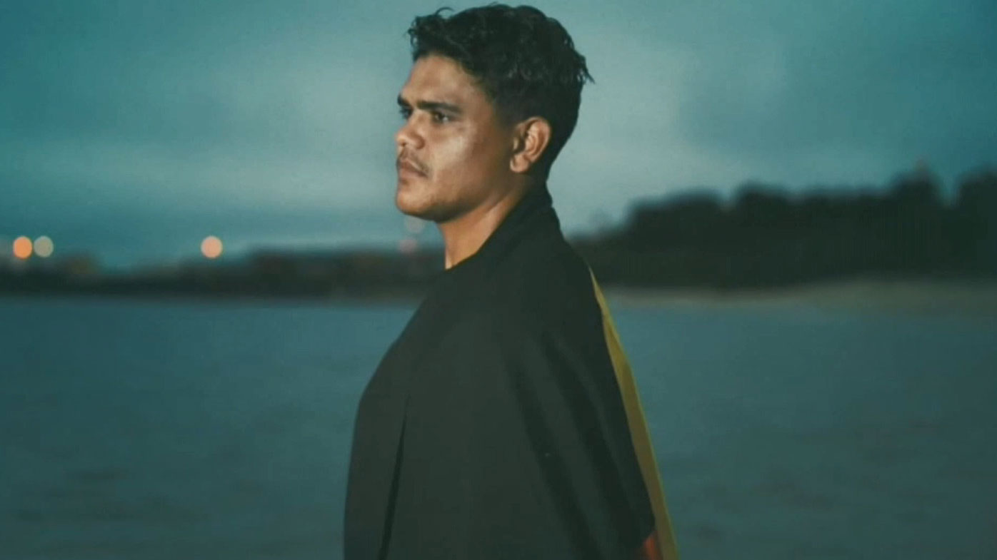 Latrell Mitchell stands with the Aboriginal flag draped around his shoulders. (NRL)