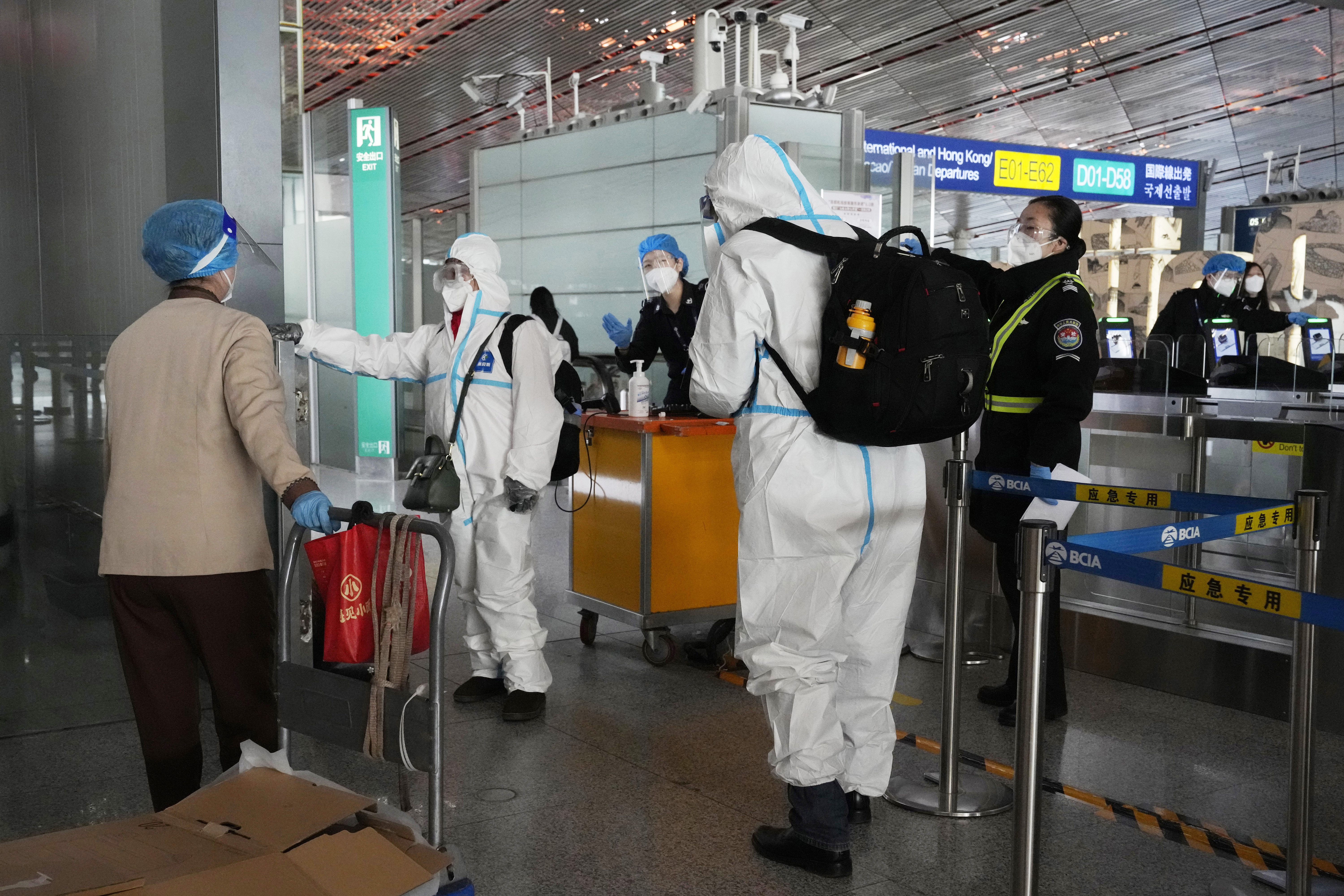 Passengers in protective gear are directed to a flight at a Capital airport terminal in Beijing on December 13, 2022. 