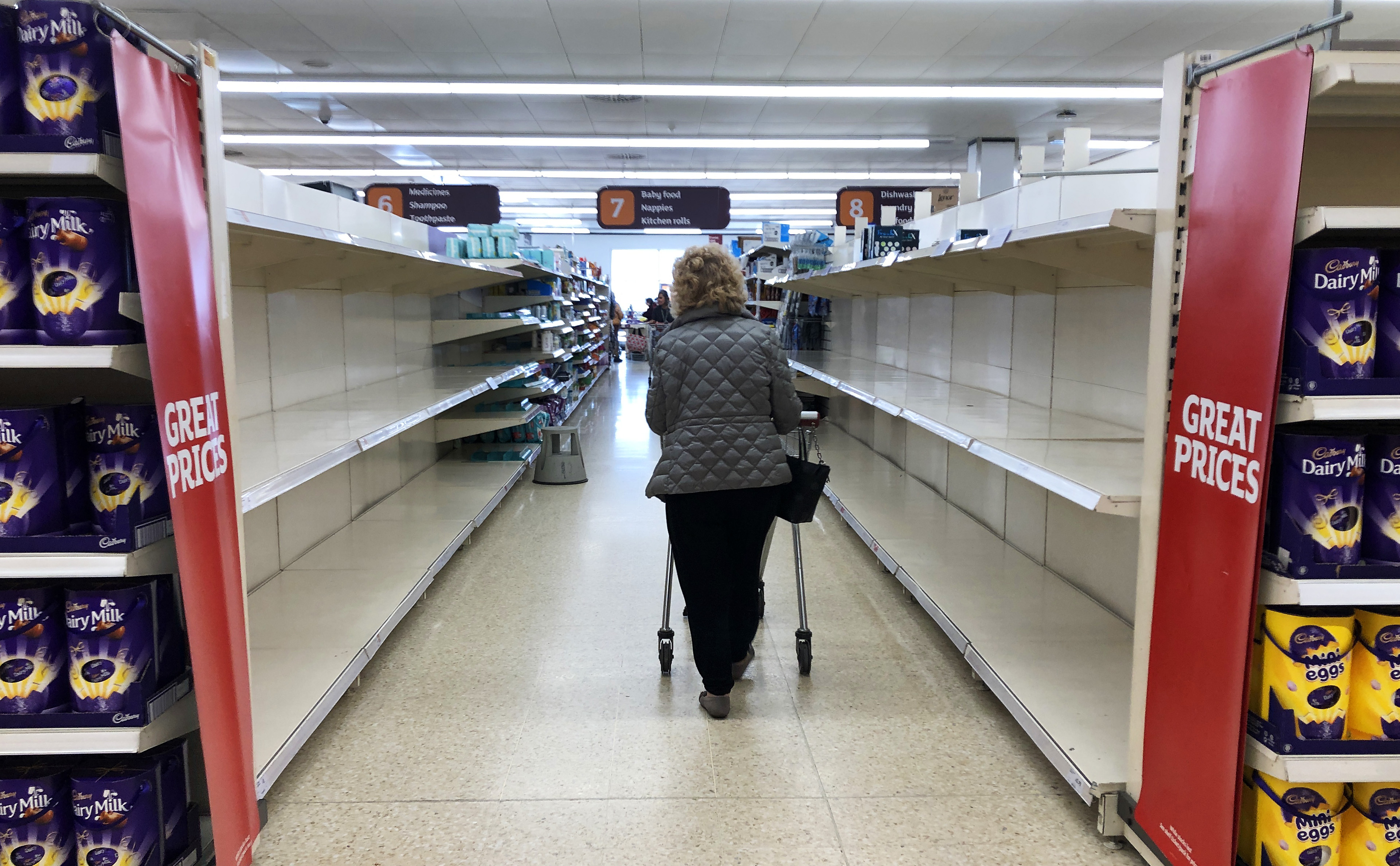 A shopper walks past empty shelves in a supermarket in the UK, where panic buying has also become a major issue. 