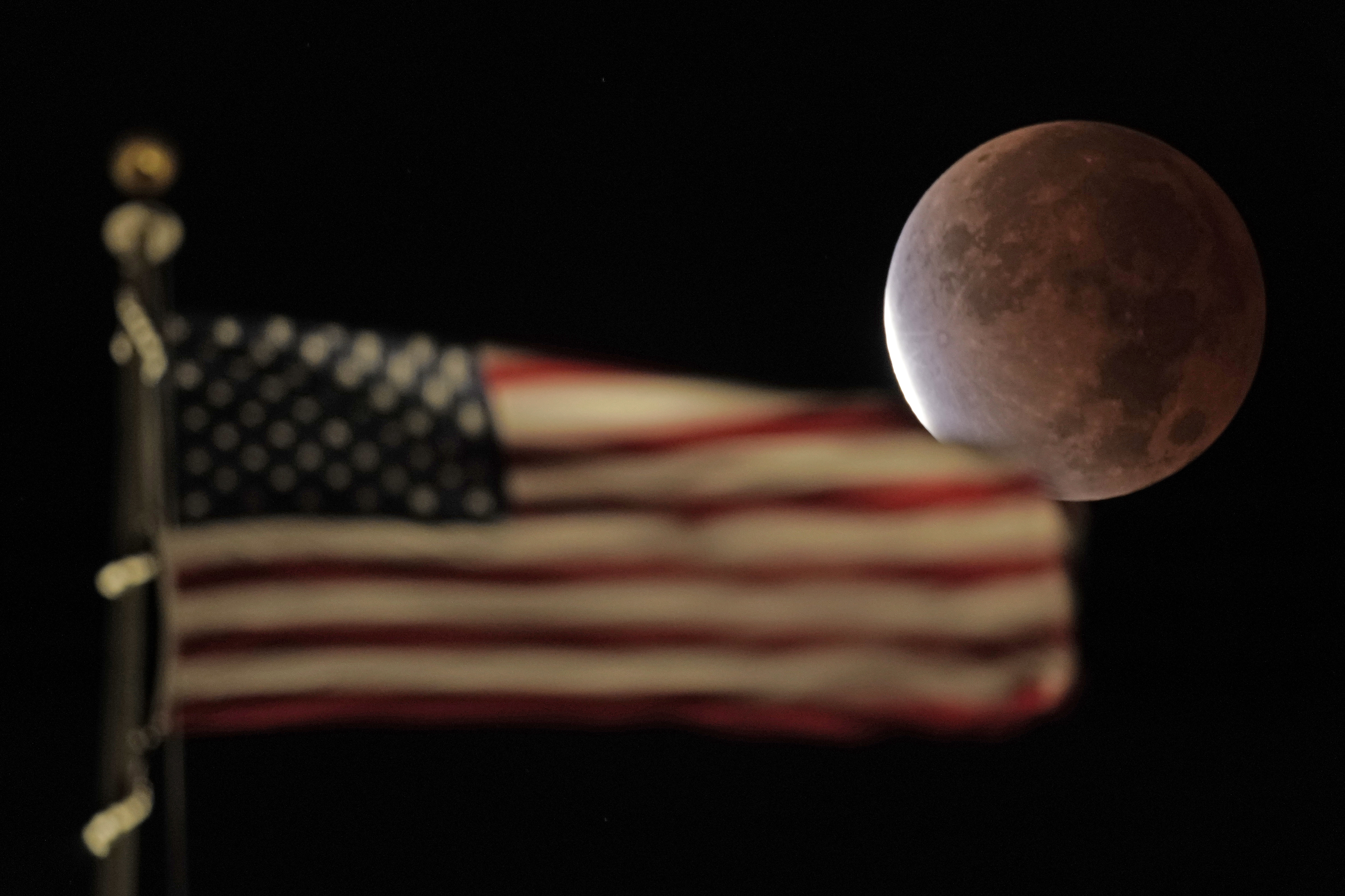 The earth's shadow covers the full moon during a partial lunar eclipse, Friday, Nov. 19, 2021, in Kansas City, Mo. (AP Photo/Charlie Riedel)
