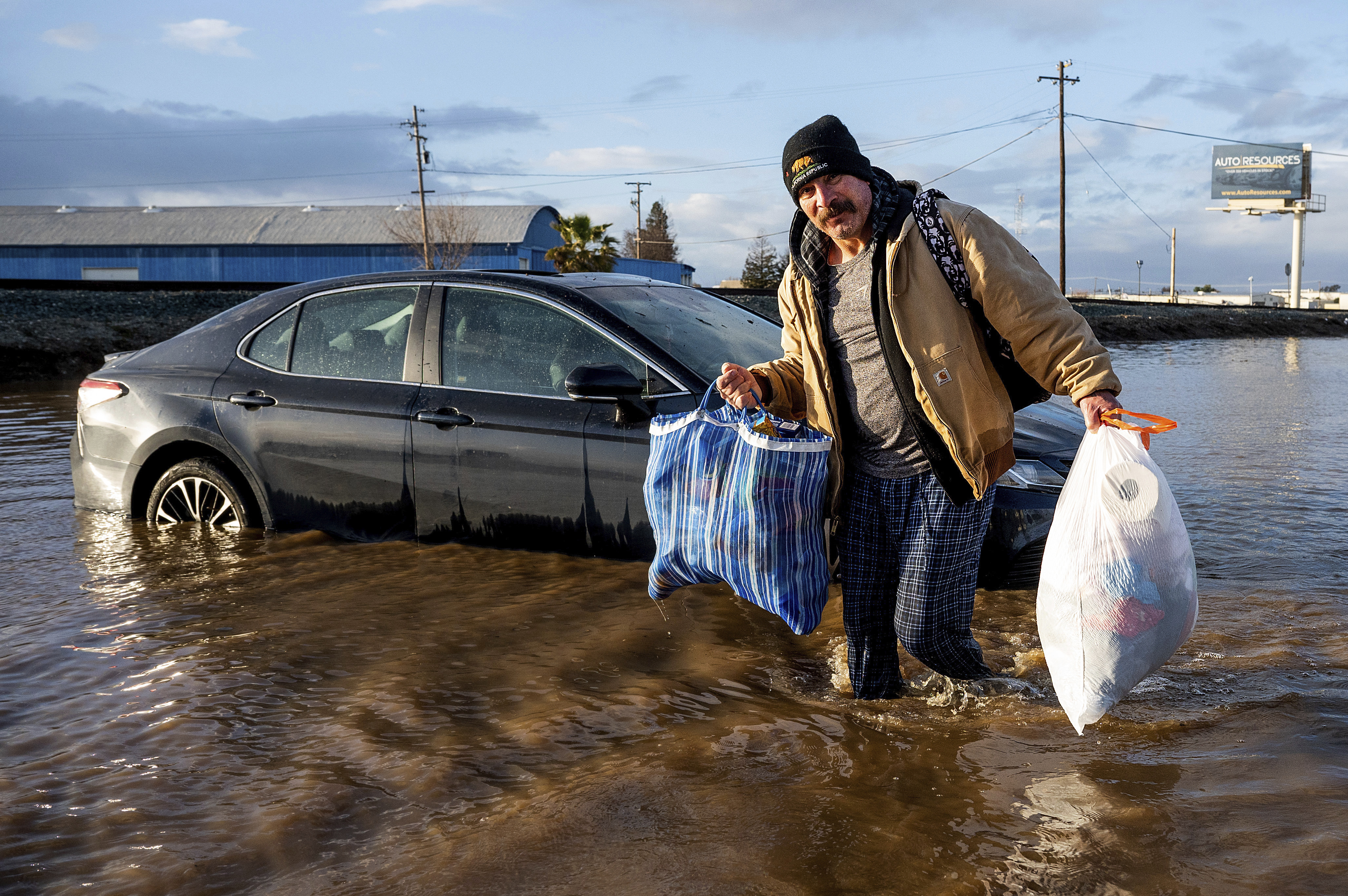 Jesus Torres carries belongings from his flooded Merced, Calif., home on Tuesday, Jan. 10, 2023.  