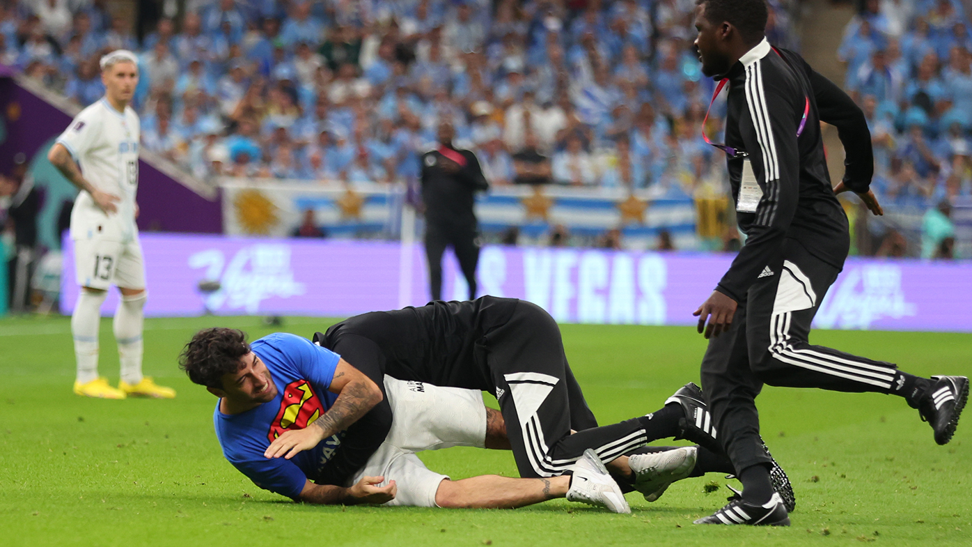 Security tackles a pitch invader during the Portugal-Uruguay match.