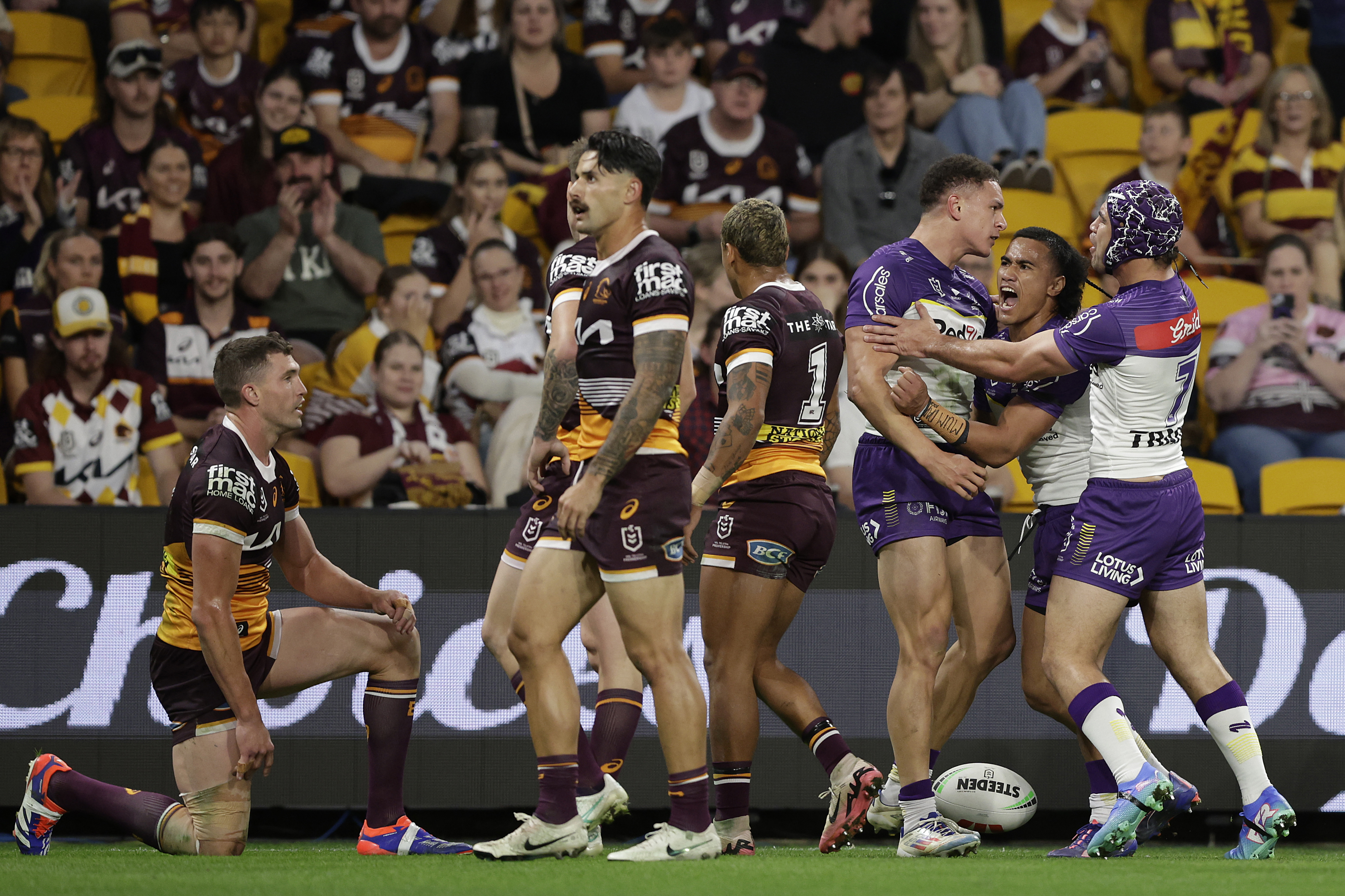 Will Warbrick of the Storm celebrates a try as Broncos players watch on.