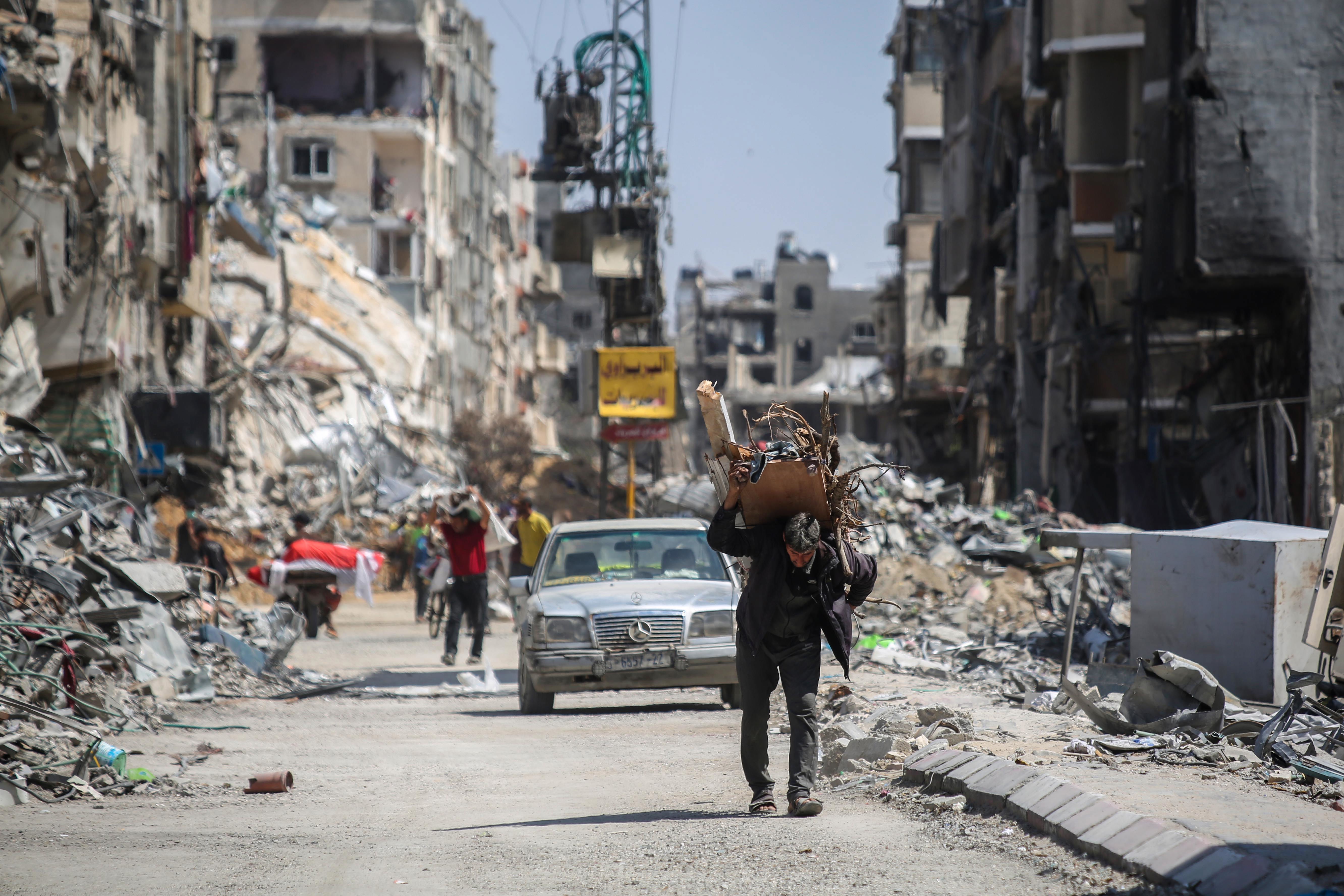 A man carries items on his back as people remove possessions from their homes following Israeli airstrikes on April 13, 2024 in Khan Yunis, Gaza. 