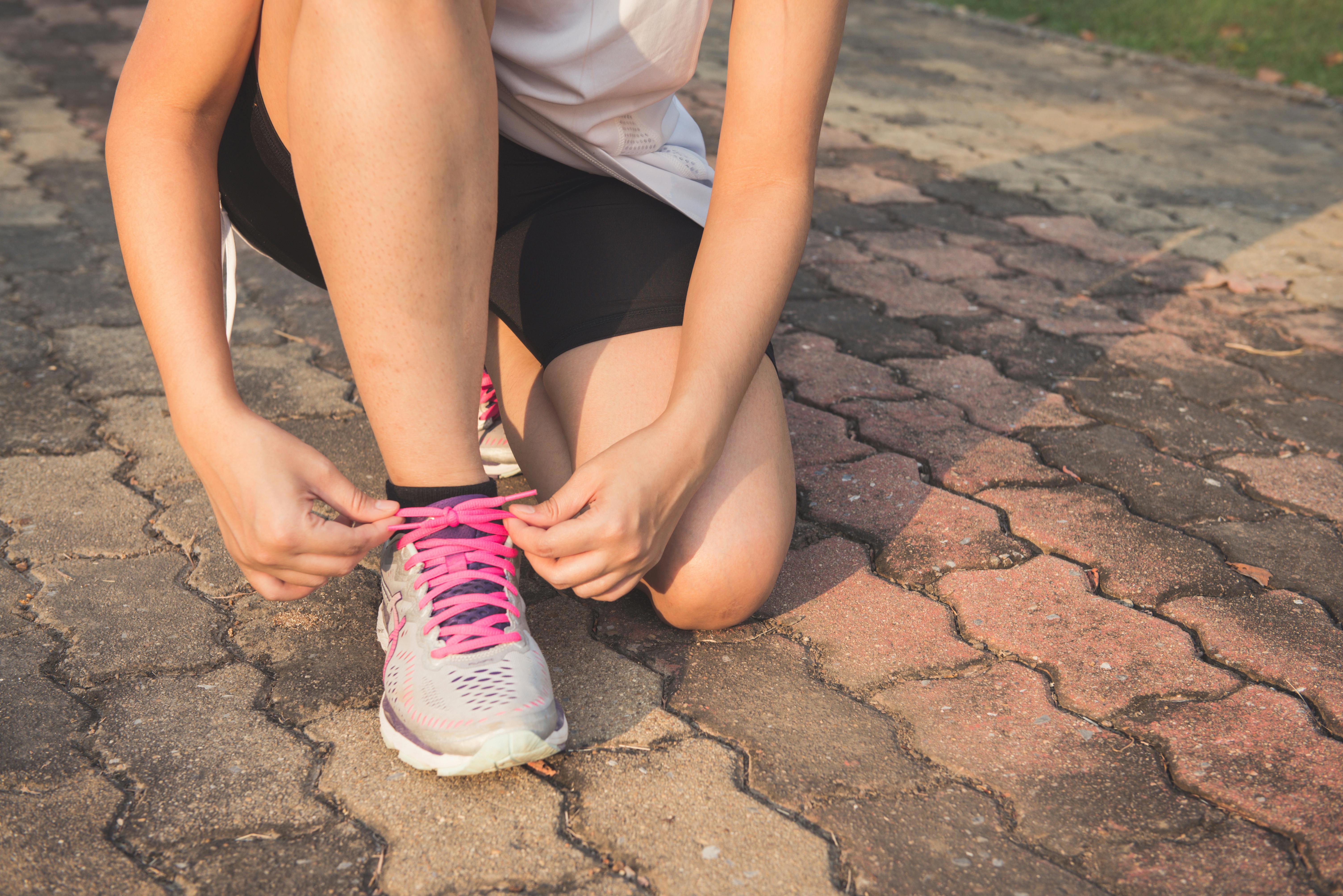 Stock image of a woman tying her shoe on a run.