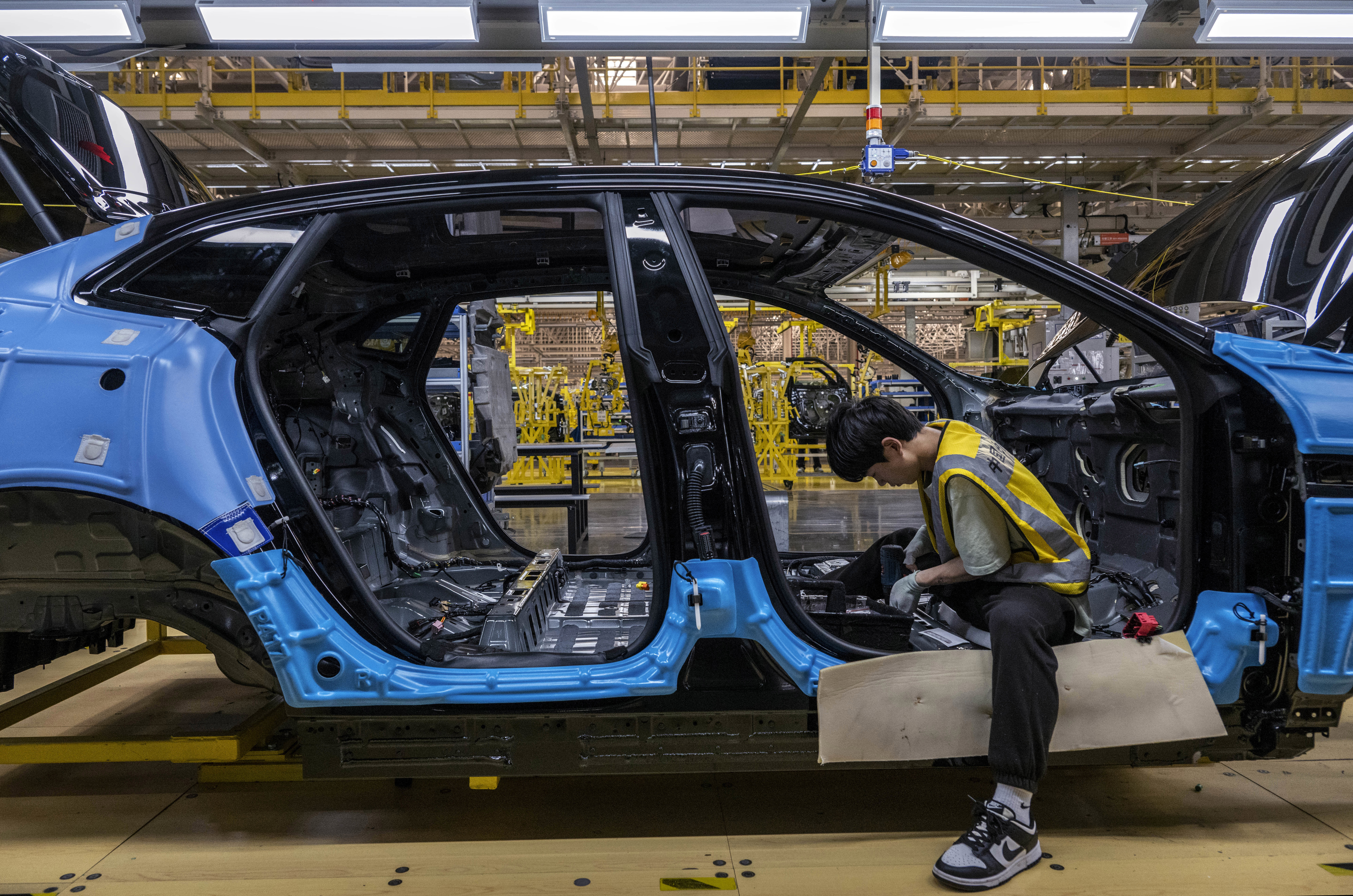 A worker adds interior pars to a car in a manufacturing plant