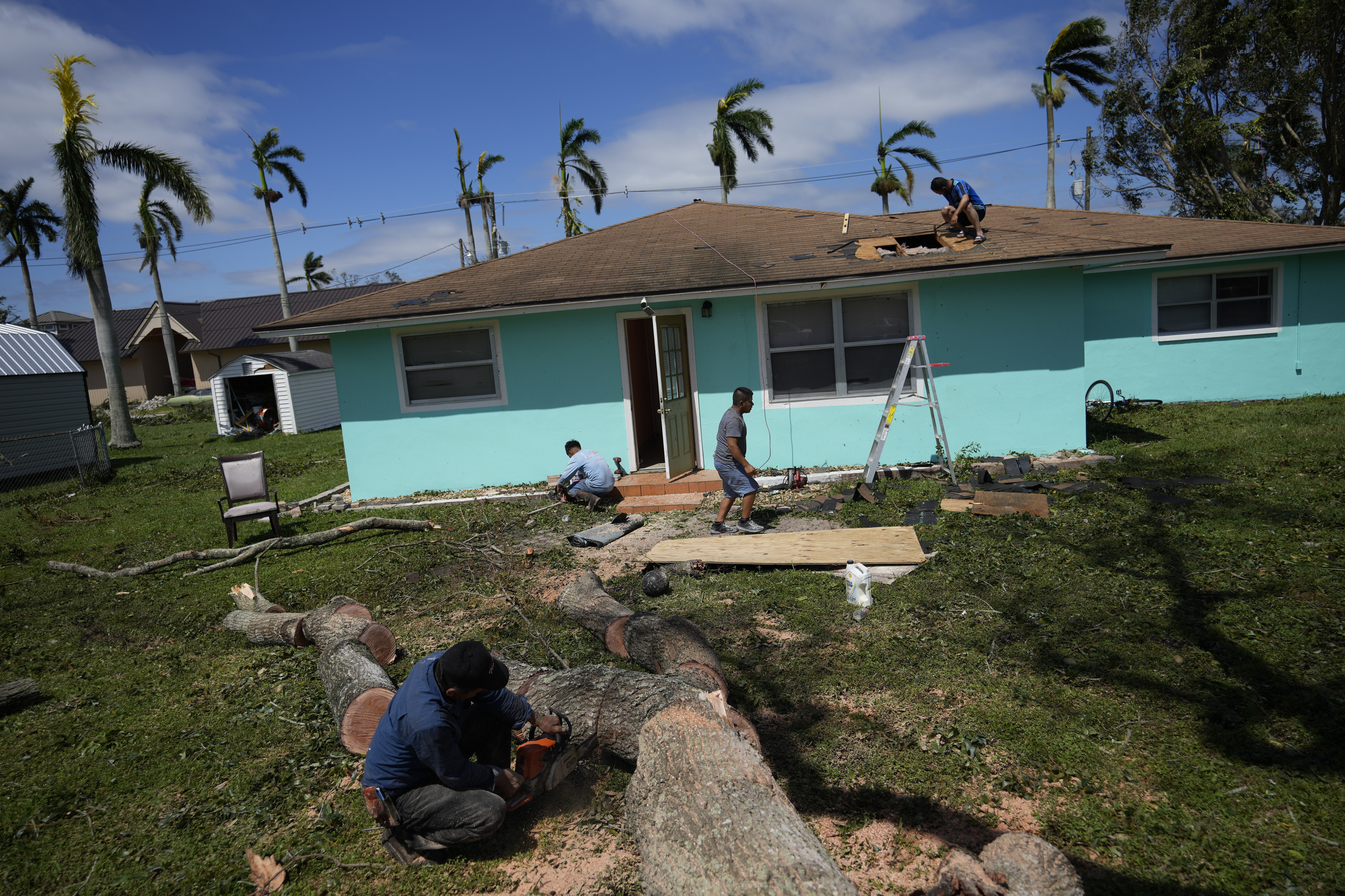 Los miembros de la familia trabajan juntos para reparar una casa después de que cayó la rama de un árbol y dañó el techo, en Fort Myers, Florida, el jueves 29 de septiembre de 2022
