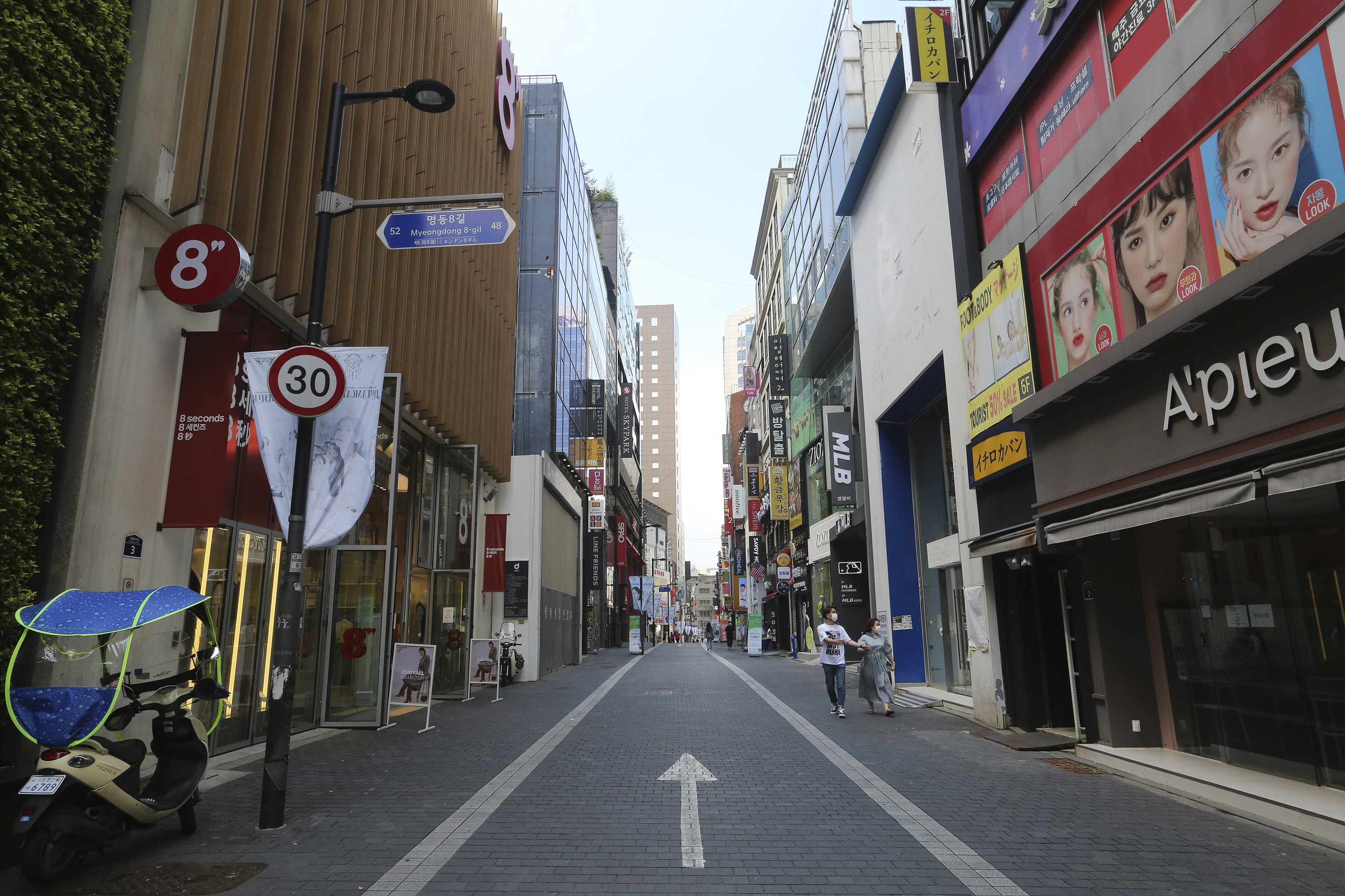 A couple wearing face masks to help protect against the spread of the coronavirus walks along on a nearly empty shopping street in Seoul, South Korea. 