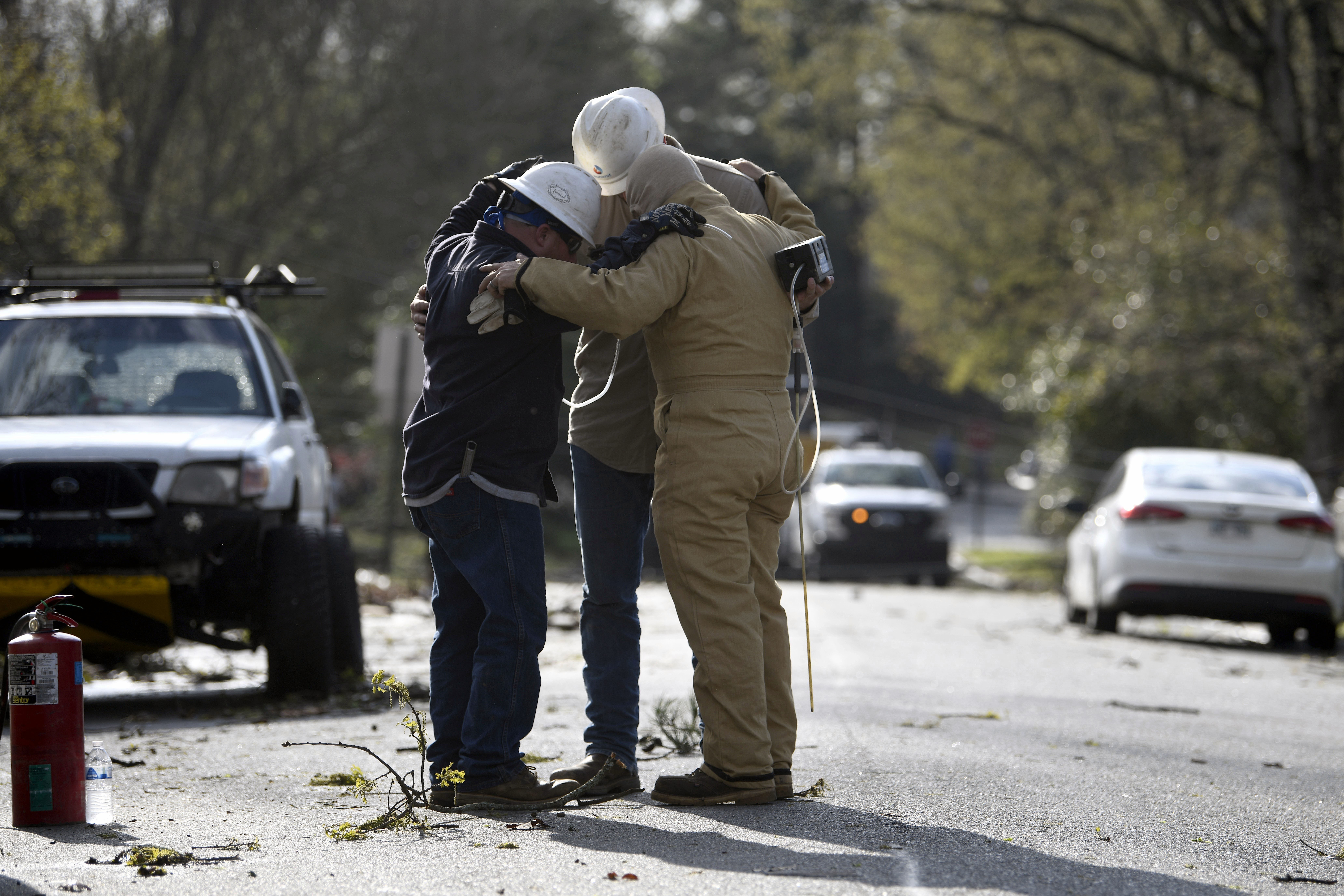 A team from Summit Energy say a prayer together before investigating a burst gas line in Cammack Village after a tornado swept through the area Friday, March 31, 2023 in Little Rock, Ark. 