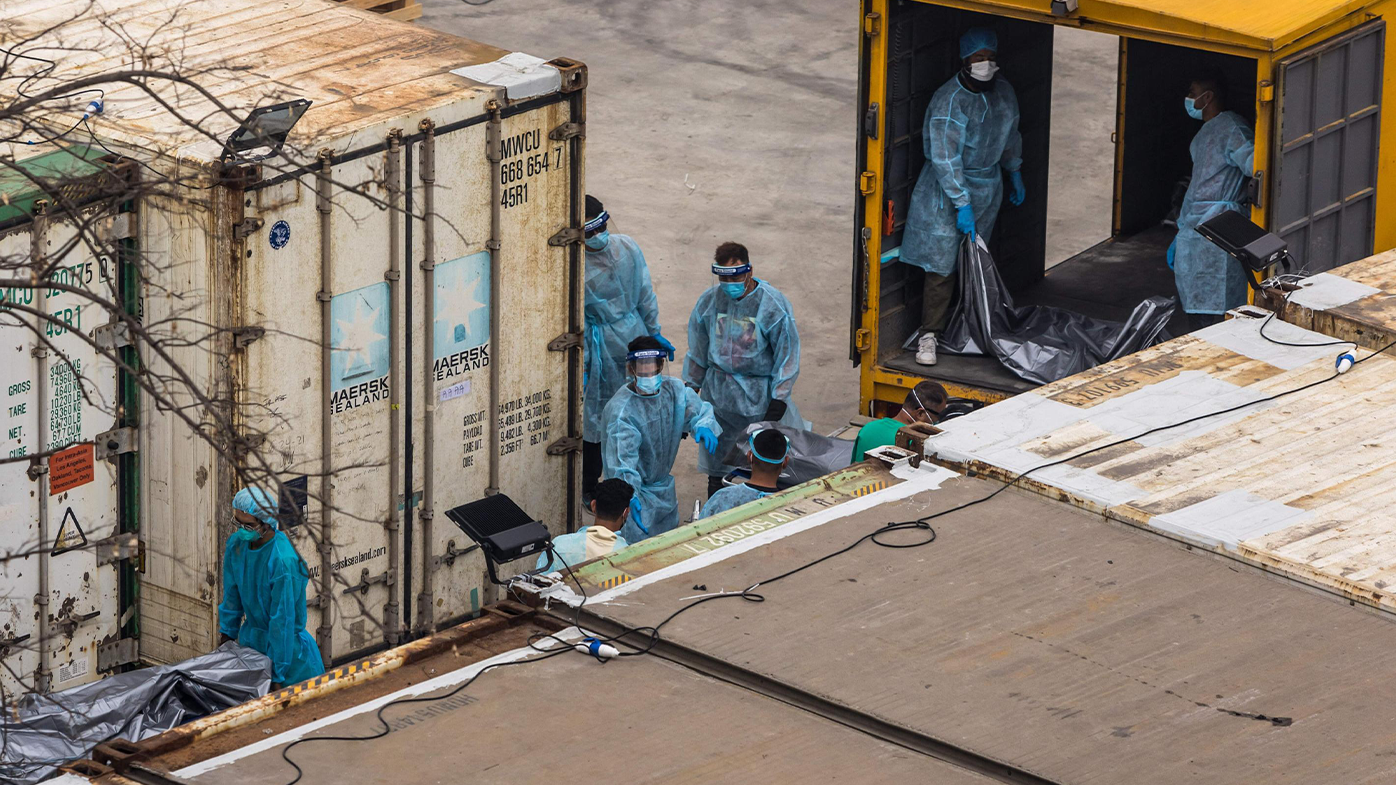 Workers move the bodies of deceased people from a truck into a refrigerated container at the Fu Shan Public Mortuary in Hong Kong on March 16, 2022, amid the city's worst-ever COVID-19 coronavirus outbreak that has seen overflowing hospitals and morgues and a frantic expansion of the city's spartan quarantine camp system.