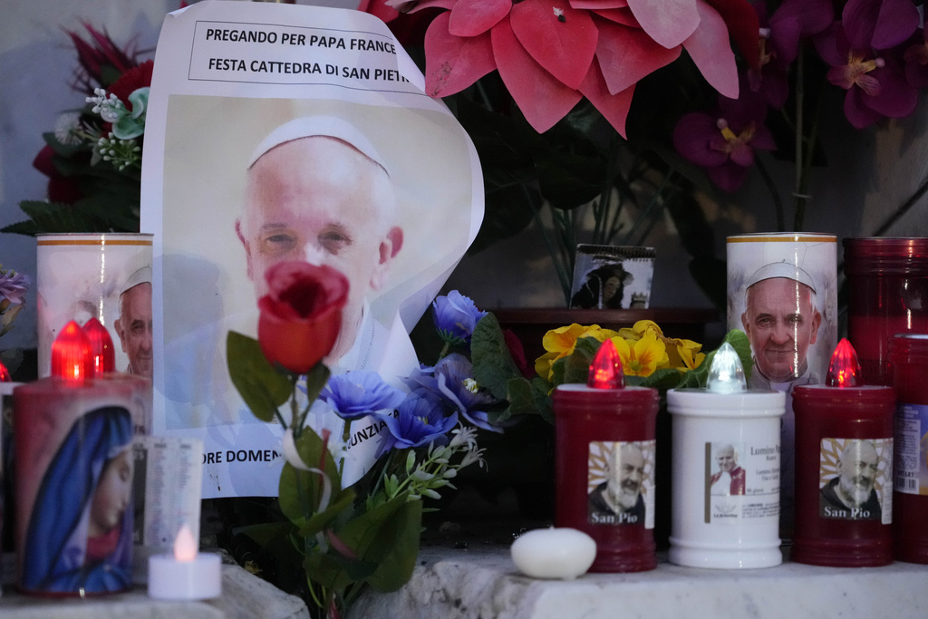 Candles are seen near pictures of Pope Francis outside the Agostino Gemelli Polyclinic in Rome, Sunday, Feb. 23, 2025, where the Pontiff is hospitalized since Feb. 14. (AP Photo/Gregorio Borgia)