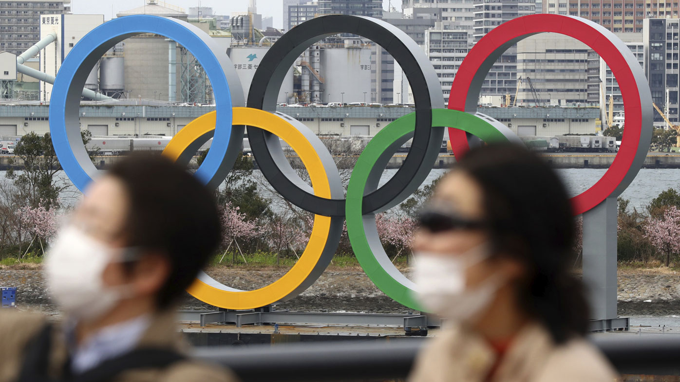 People wearing a mask walk near the Olympics' mark in Odaiba, Tokyo on February 22, 2020, amid the outbreak of a new coronavirus in Japan. 