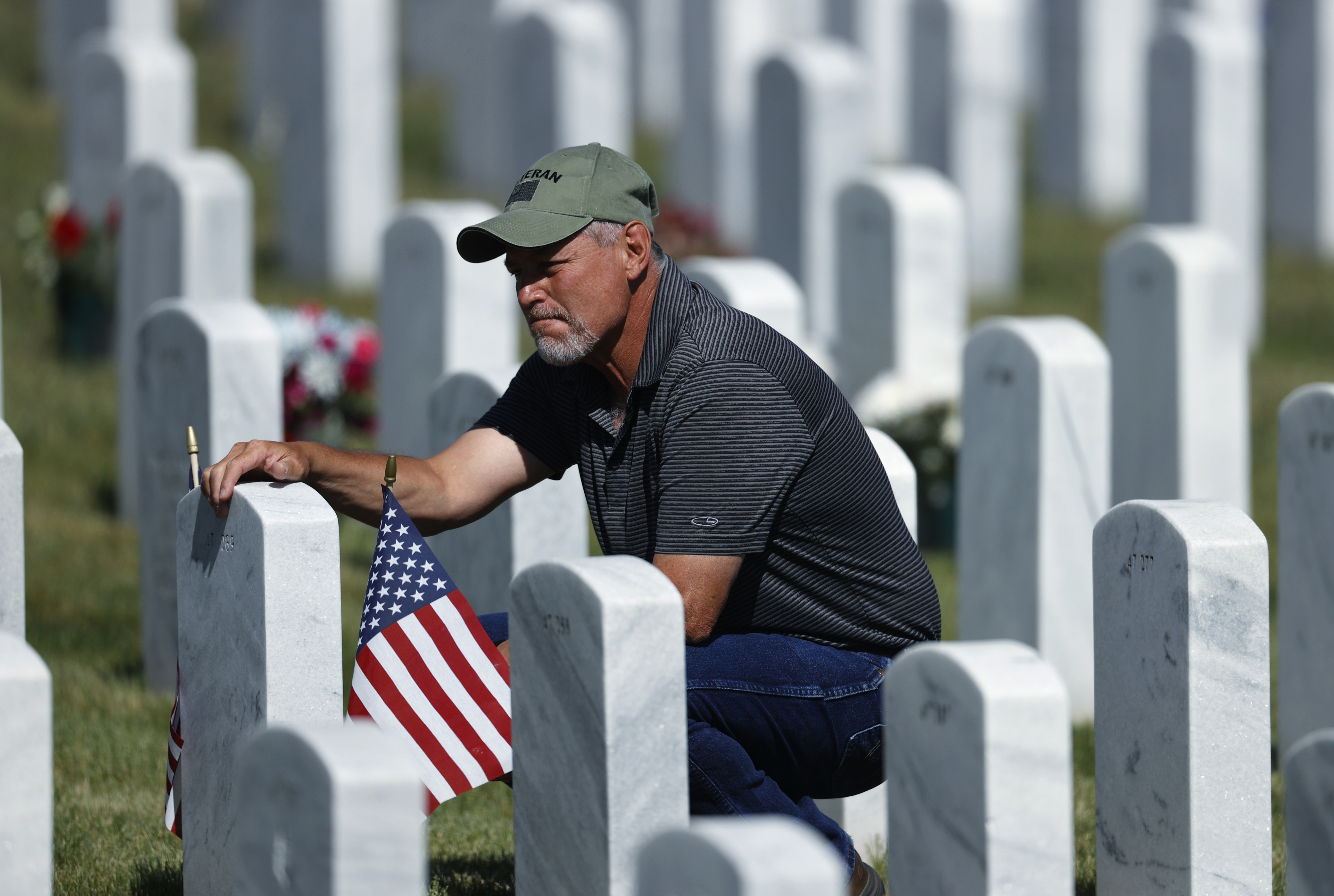 J.D. Madrid pauses to pay tribute at the grave of his father-in-law, Michael McBrien, at Fort Logan National Cemetery on Memorial Day