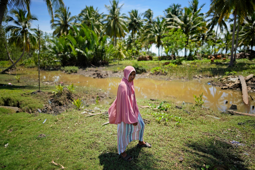 Munirpa, a crocodile attack survivor, stands for a portrait at the location where she was nearly killed by a four-meter-long crocodile, in Topoyo, West Sulawesi, 