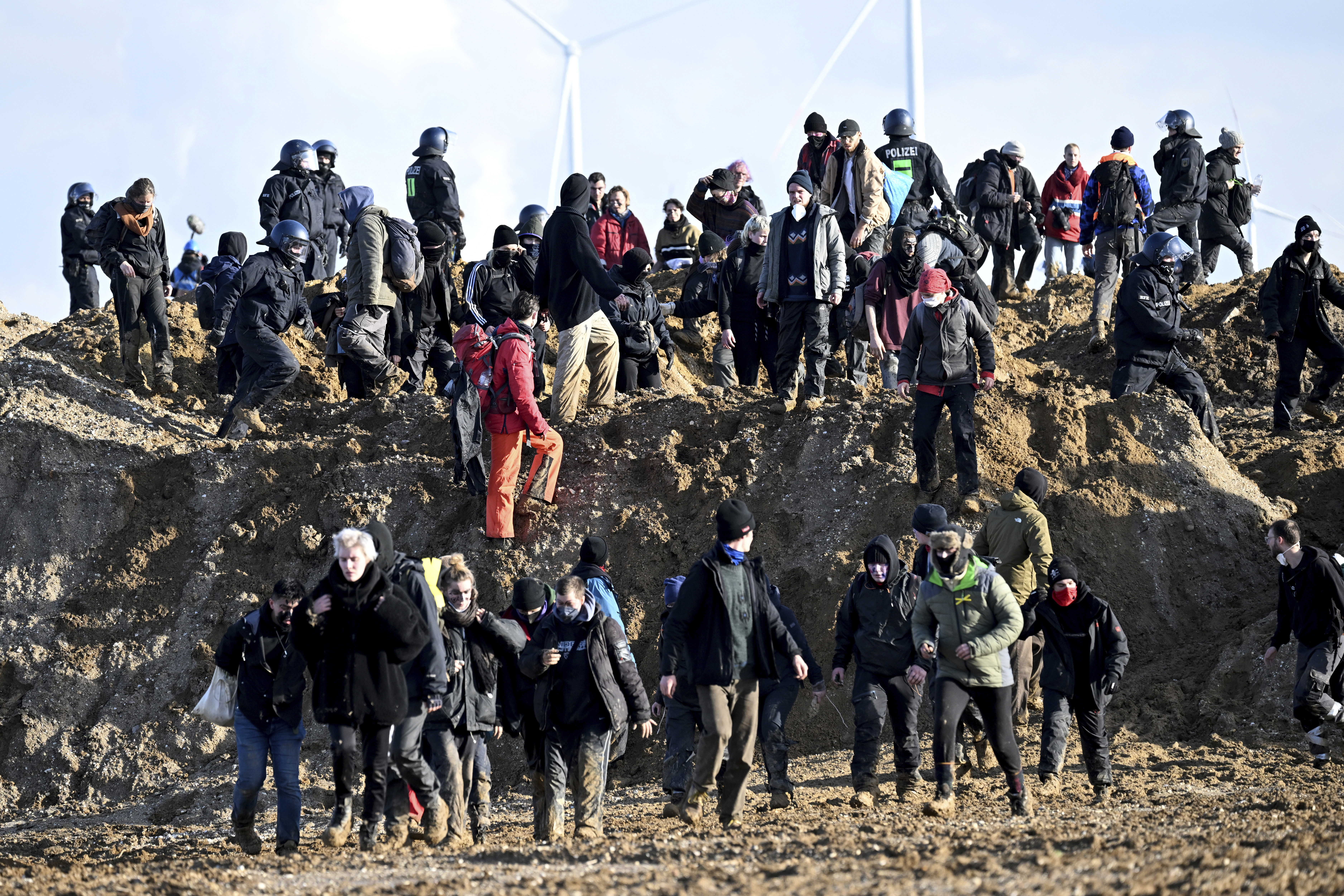  Activists and coal opponents walk along the demolition edge of the Garzweiler II opencast lignite mine during a protest by climate activists after the clearance of Luetzerath, with police officers standing in between in Erkelenz, Germany, Tuesday, Jan. 17, 2023. 