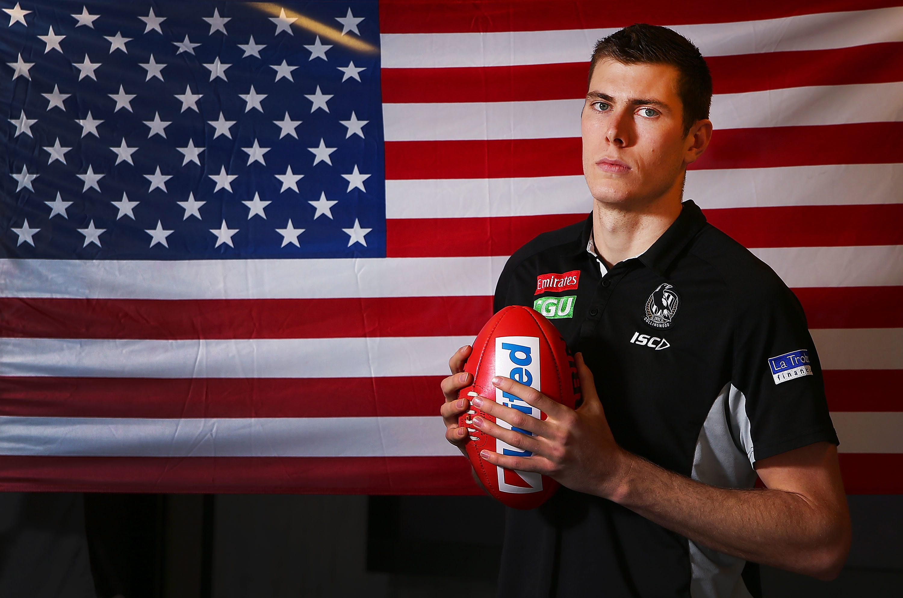 Mason Cox, the first American to play in the AFL, poses in front of his national flag.