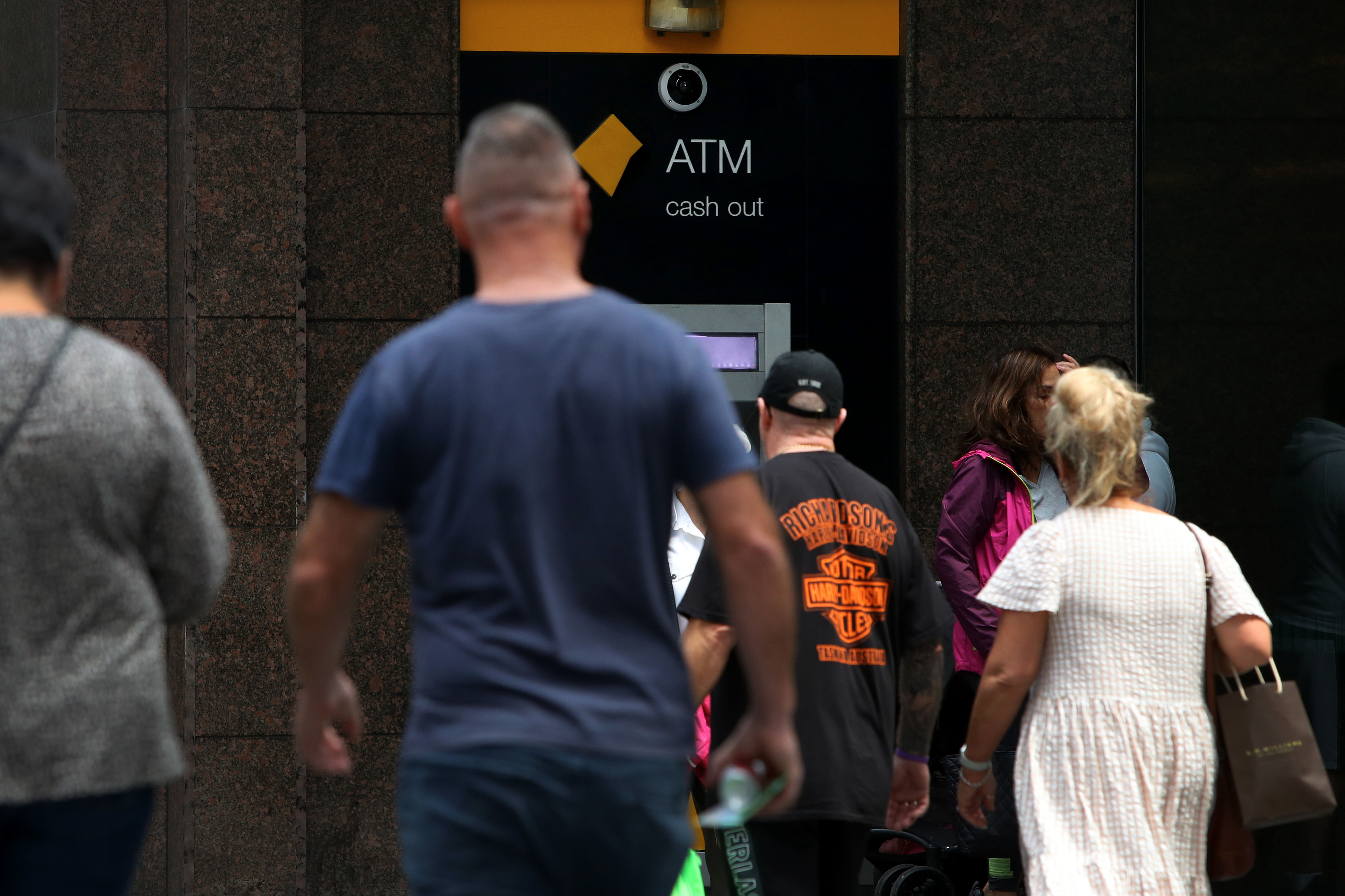 People move past a Commonwealth Bank ATM machine.