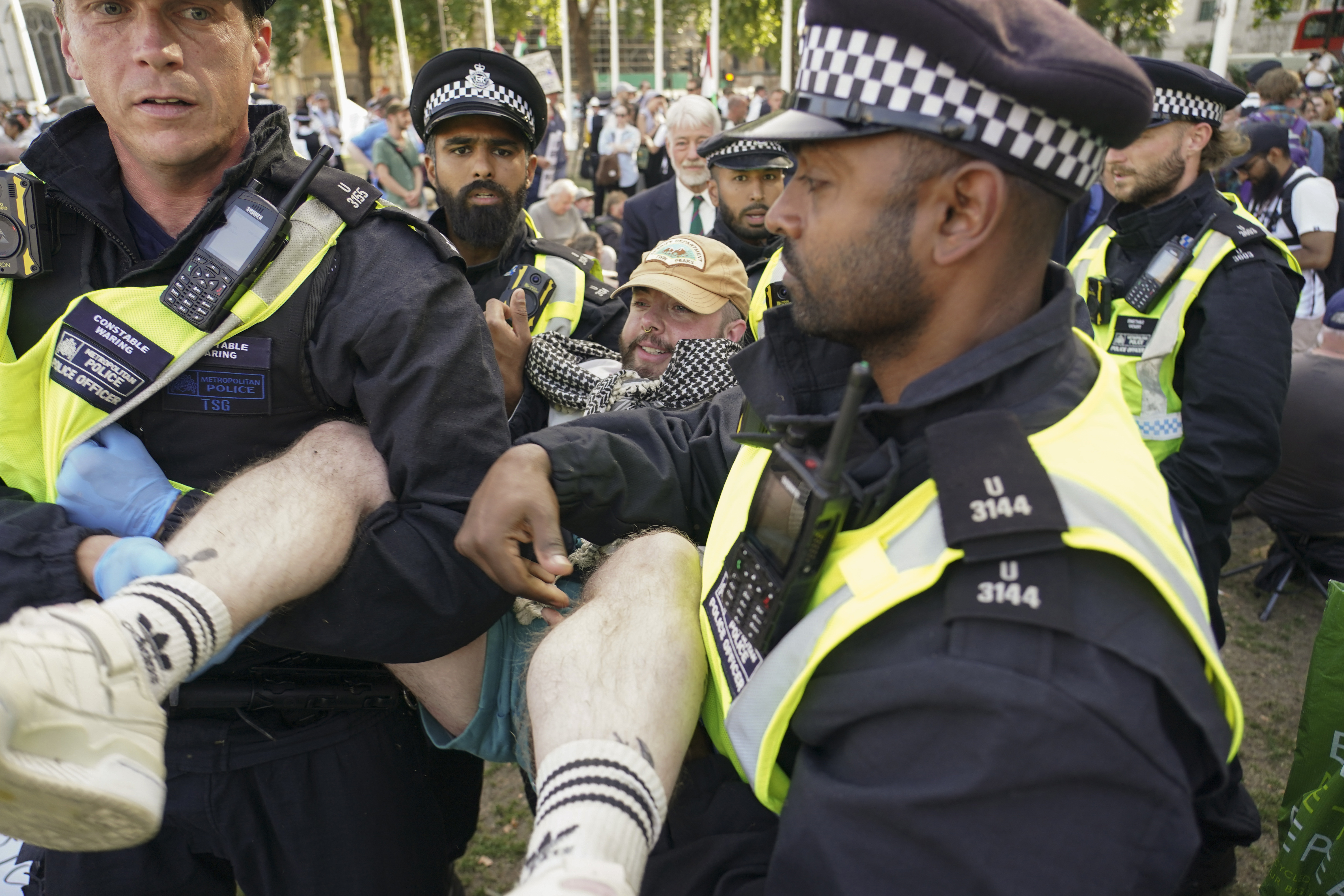 Police officers arrest a demonstrator during a protest in support of the Palestinian people, in Parliament Square, in London