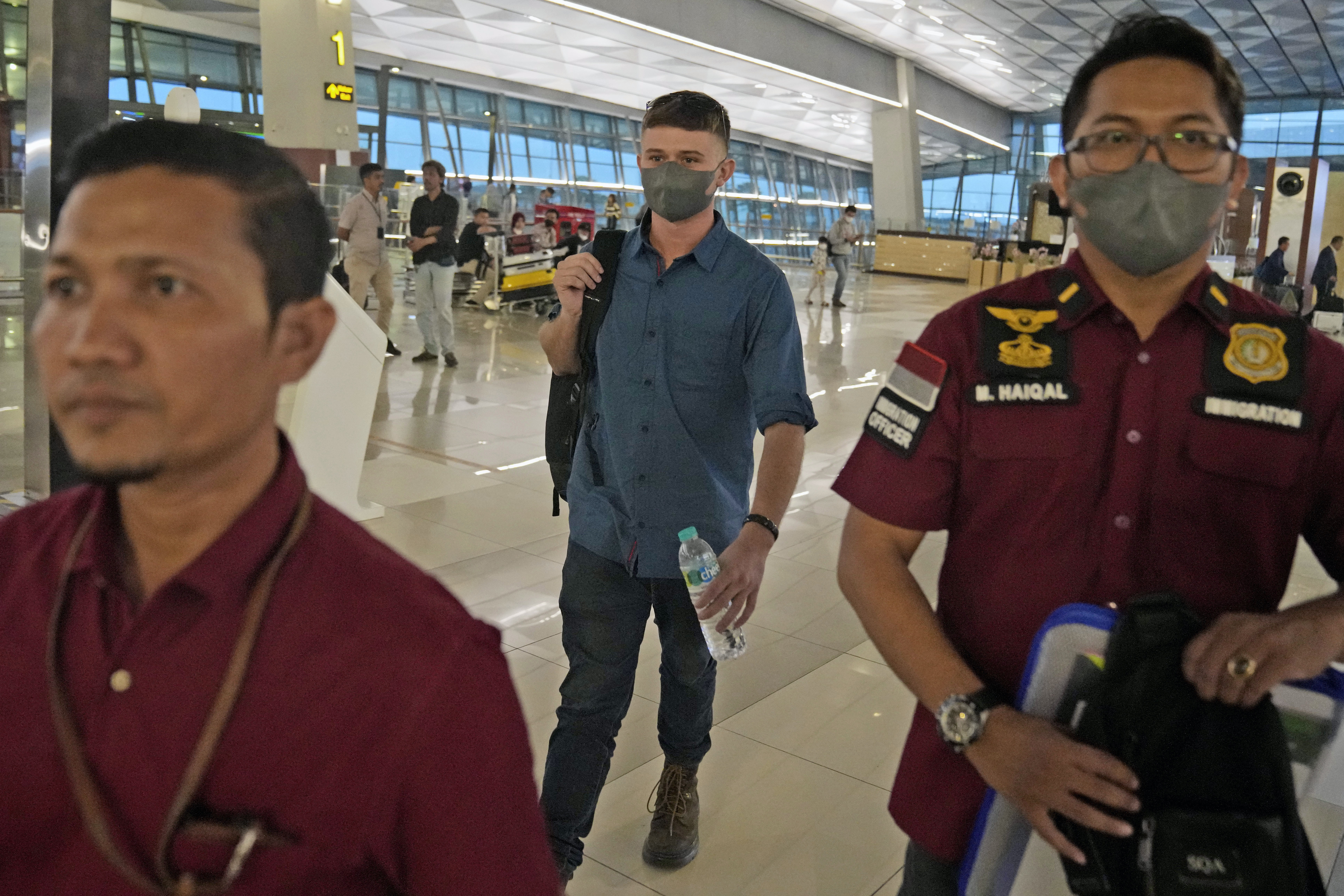 Australian national Bodhi Mani Risby-Jones from Queensland, center, walks with his lawyer Idris Marbawi, left, and an immigration officer upon arrival at Soekarno-Hatta International Airport in Tangerang, Indonesia, Saturday, June 10, 2023. 