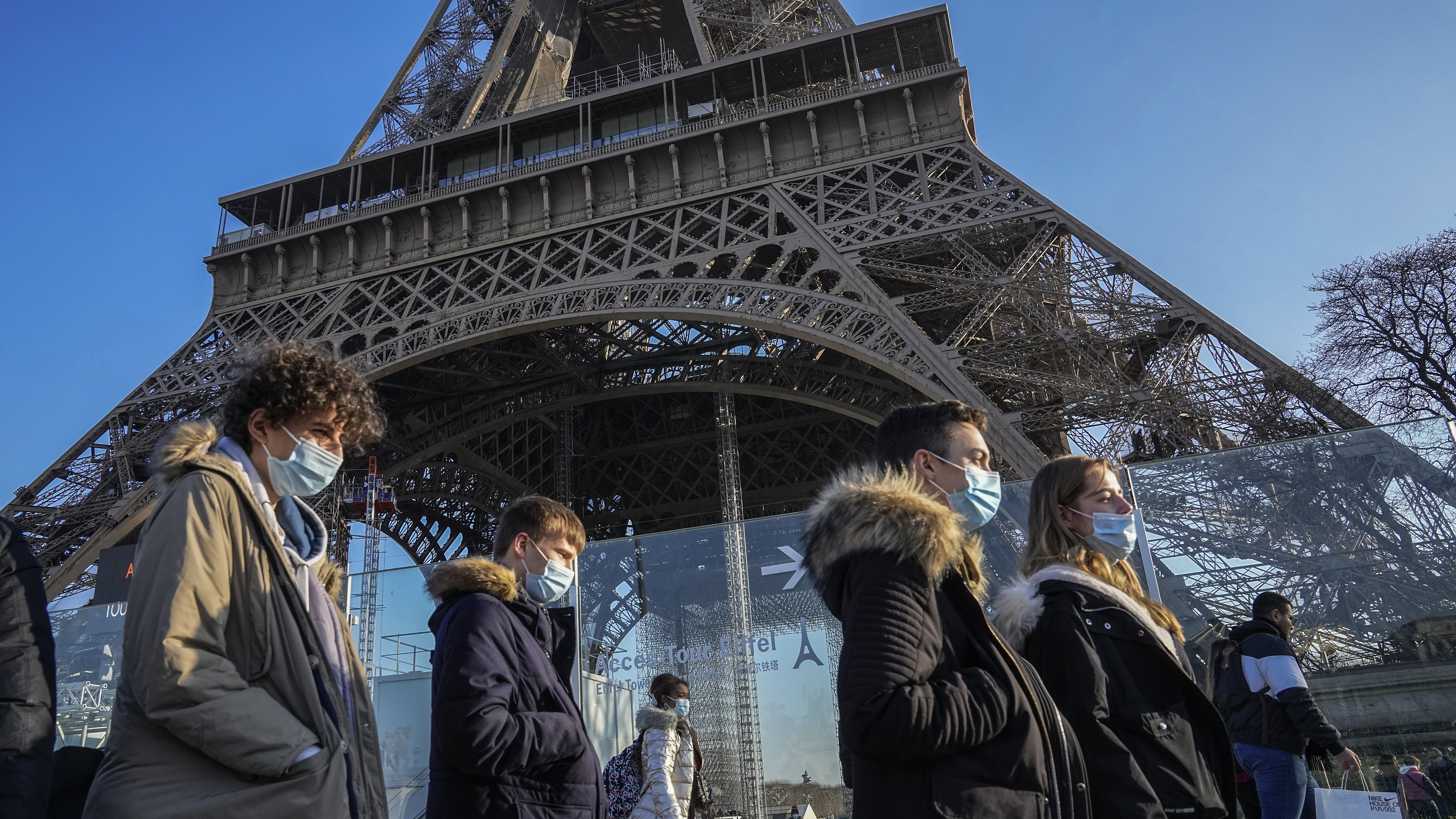 People wearing face masks to protect against COVID-19 walk past the Eiffel Tower in Paris, 