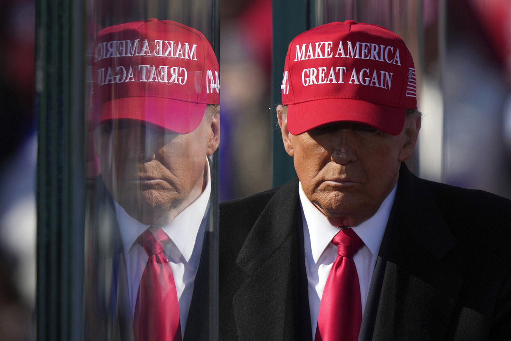 FILE - Republican presidential nominee former President Donald Trump is reflected in the bullet proof glass as he finishes speaking at a campaign rally in Lititz, Pa., Nov. 3, 2024. (AP Photo/Matt Rourke, File)