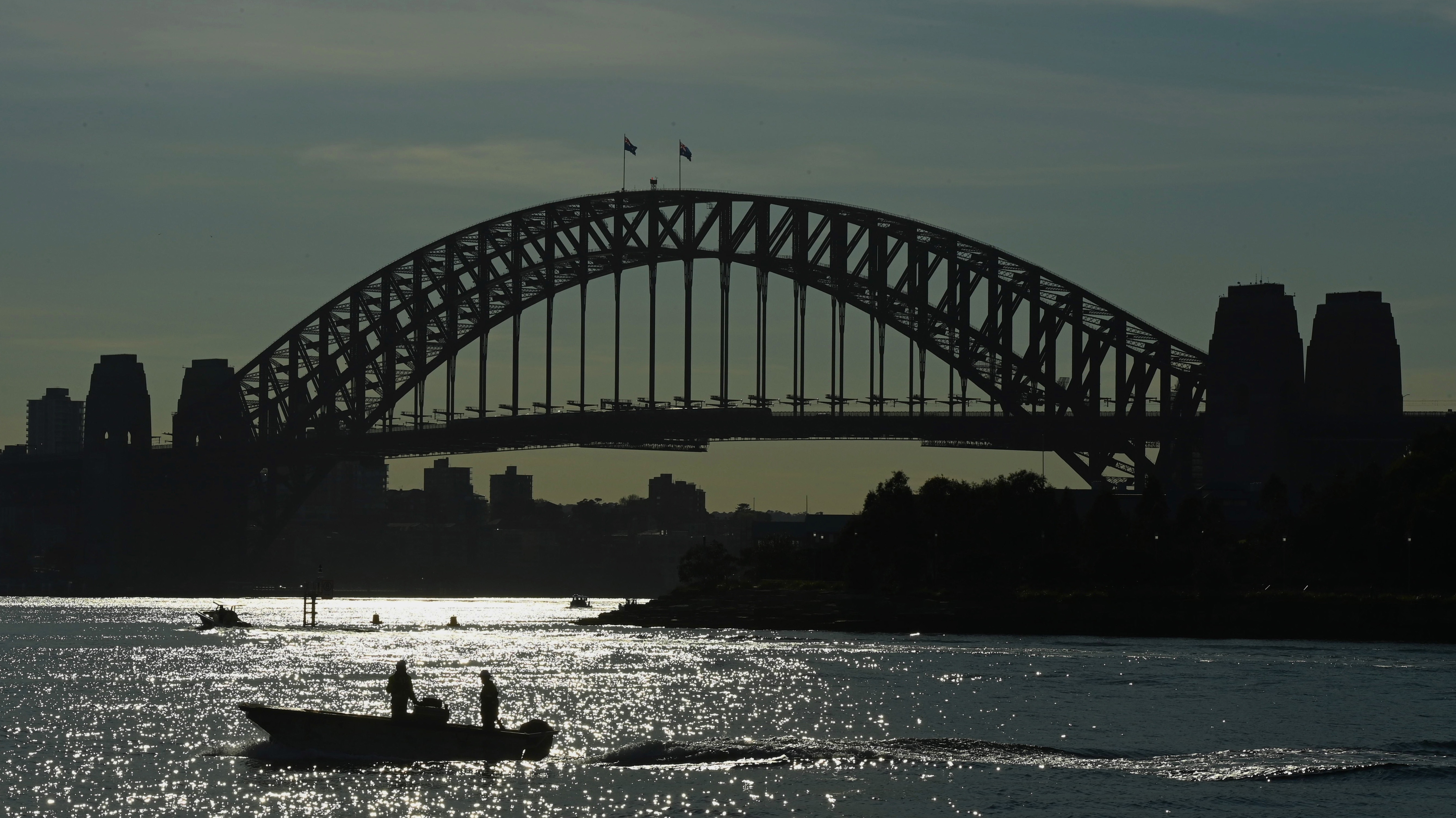 Two men in a boat pass the Sydney Harbour Bridge near East Balmain during the NSW statewide COVID-19 lockdown. 