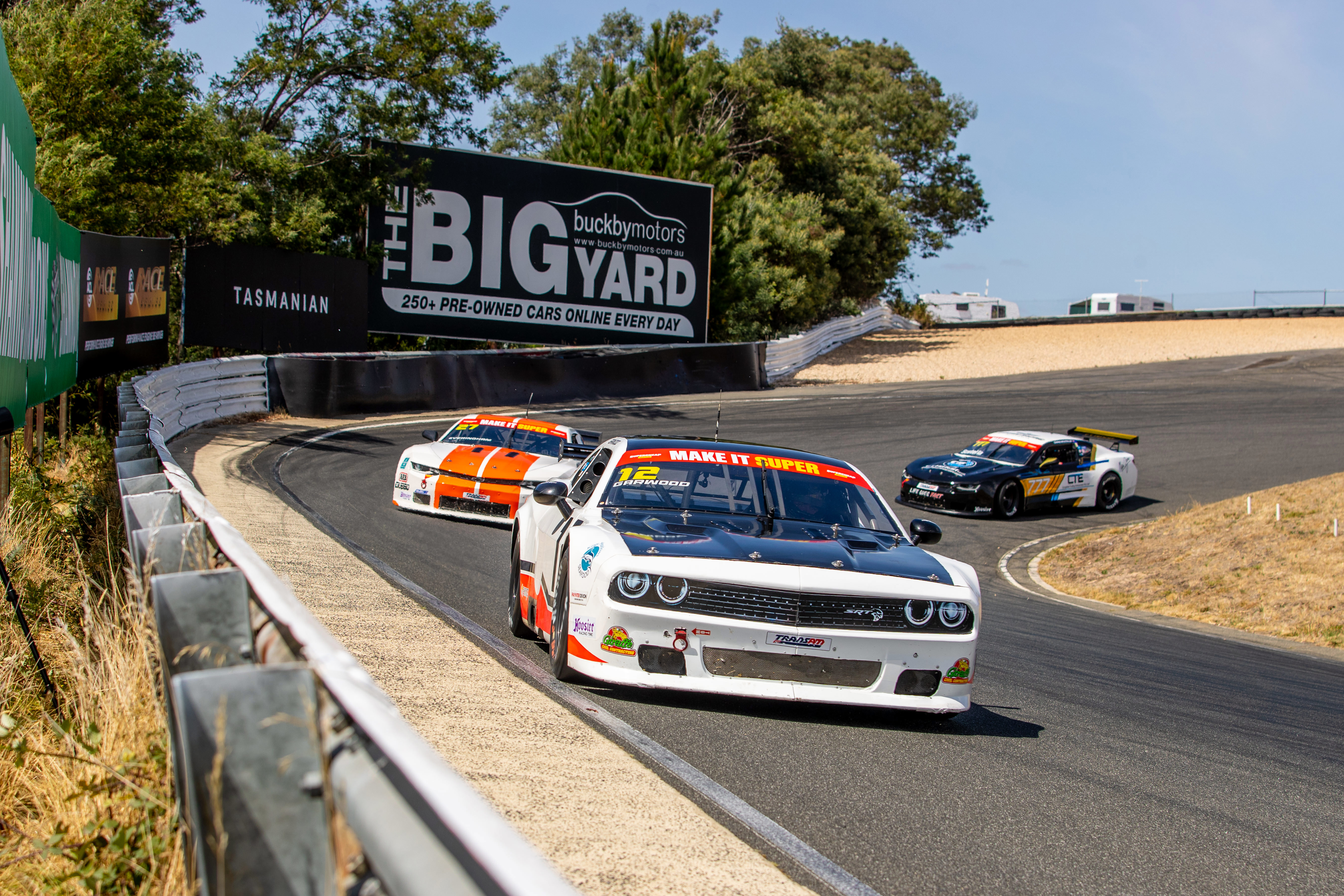 A TA2 Dodge Challenger followed by two Chevrolet Camaros.