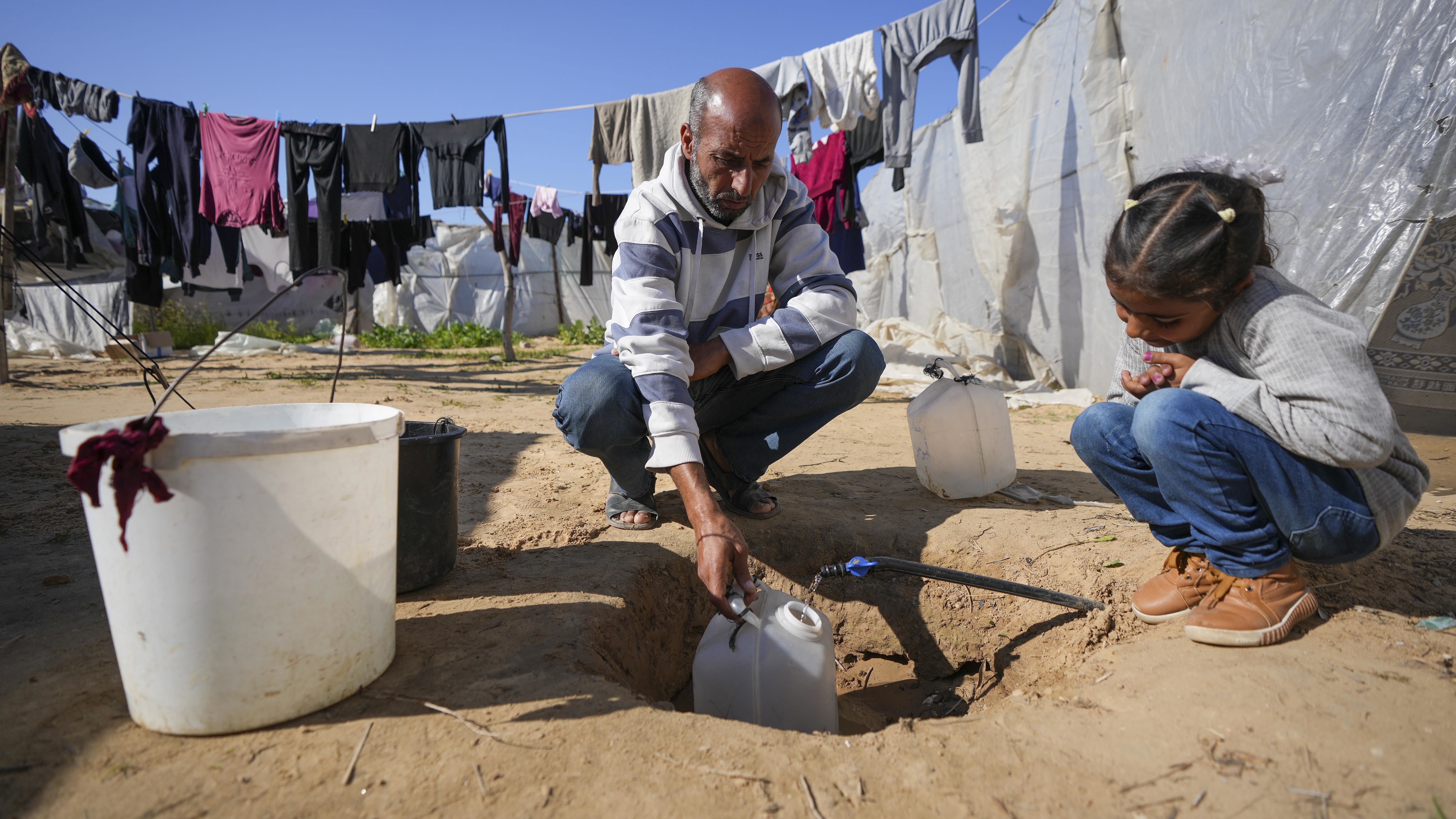 Ne'man Abu Jarad recoge agua mientras él y su familia se preparan para regresar a su casa en el norte, en un campamento para palestinos desplazados en el área de Muwasi, Southern Gaza Strip.