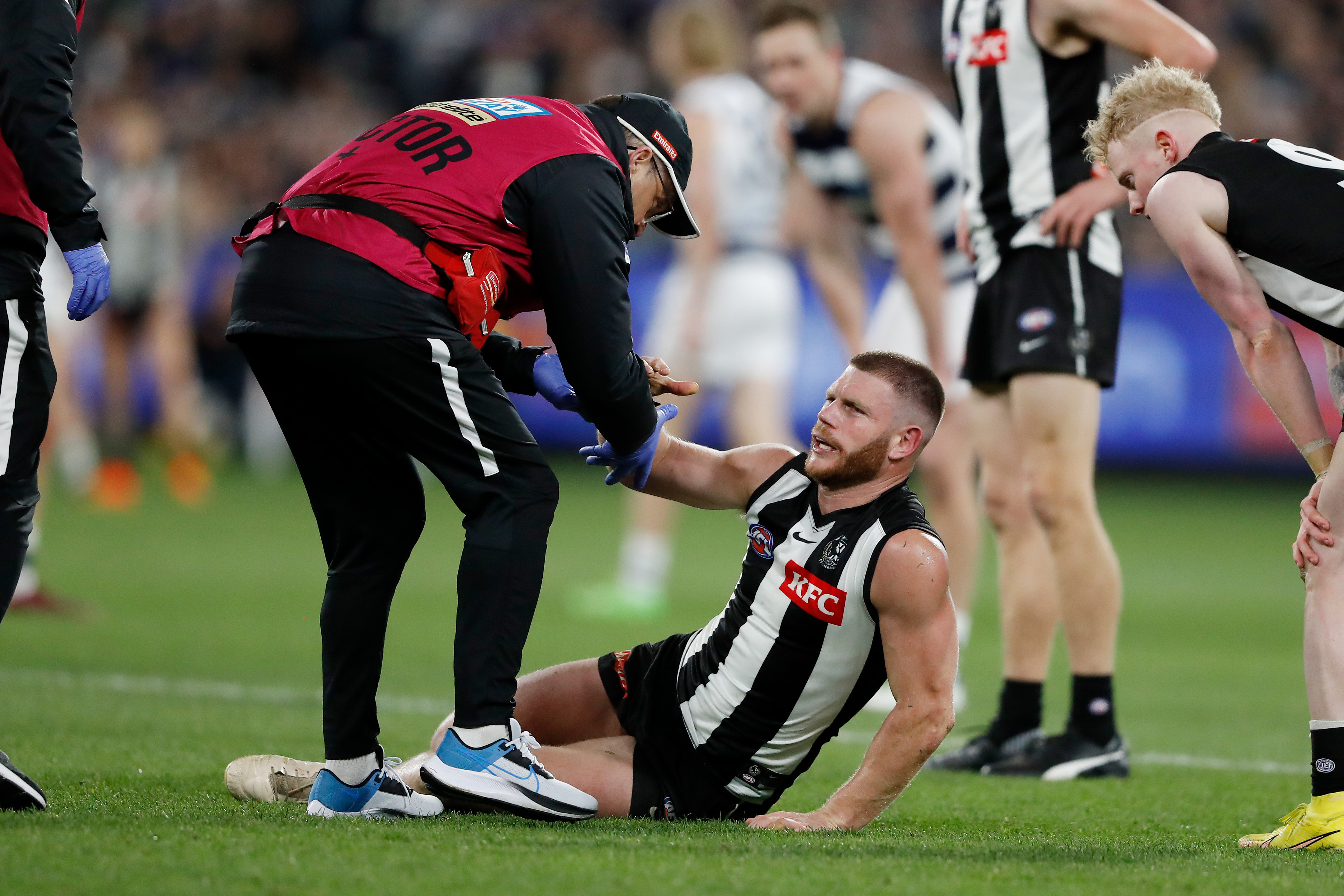 Taylor Adams of the Magpies is seen being assisted off the ground by medical staff during their qualifying final.