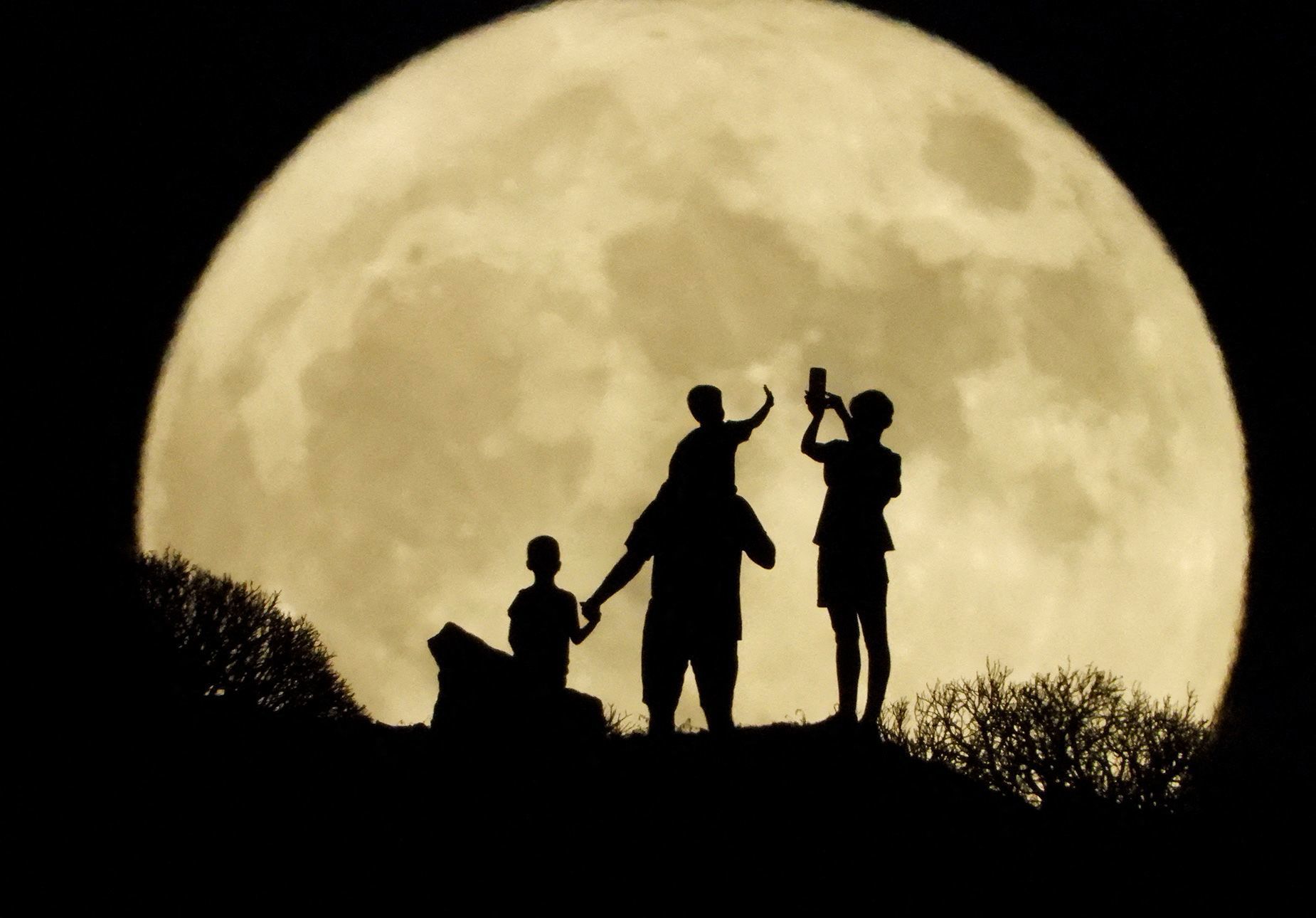 A family stand with the full moon known as the "Sturgeon Moon"