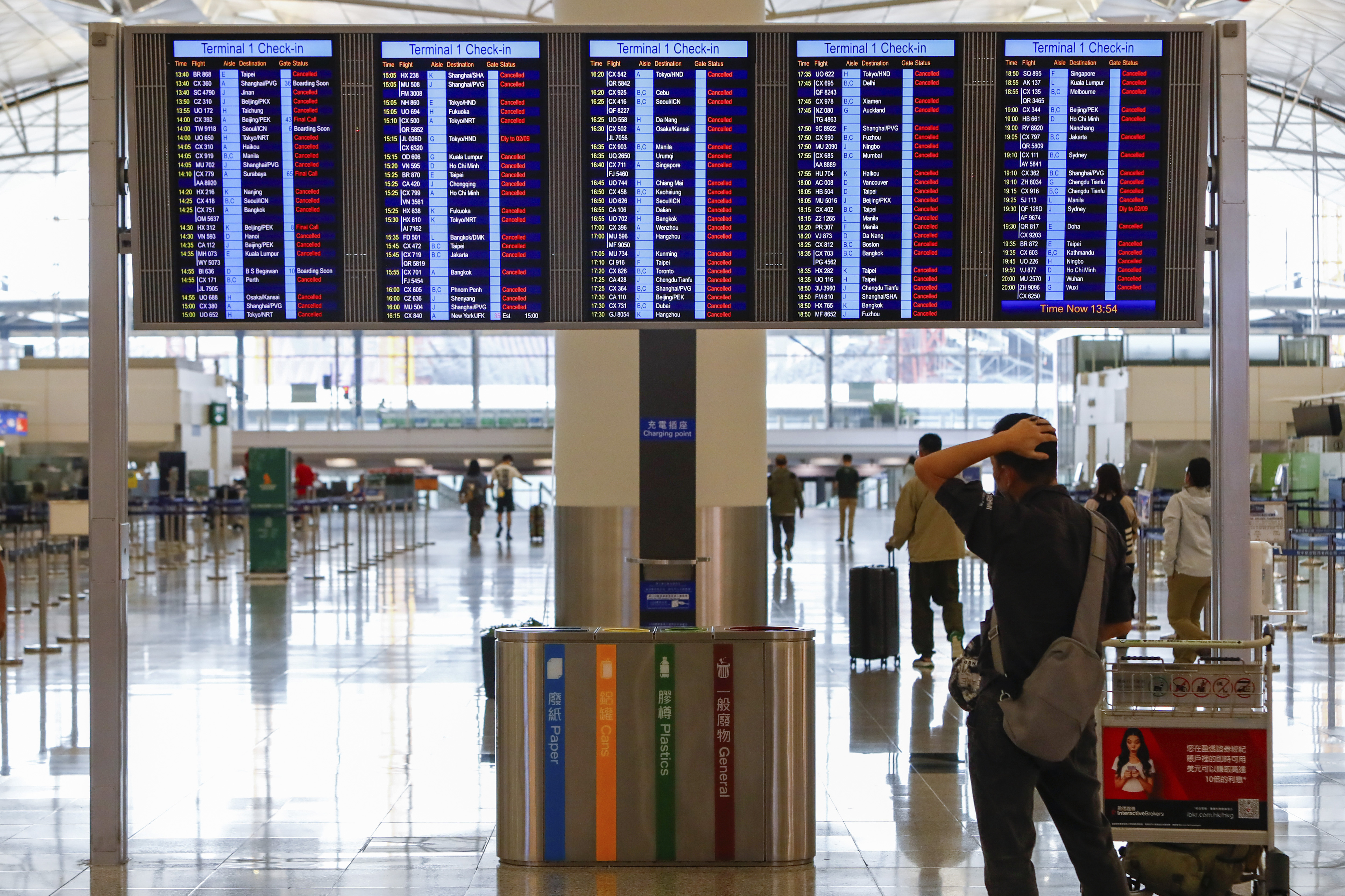 A passenger looks at an information display which shows almost all of the flights have been canceled due to the super typhoon Saola, at Hong Kong International Airport, in Hong Kong, on Friday, Sept. 1, 2023. 