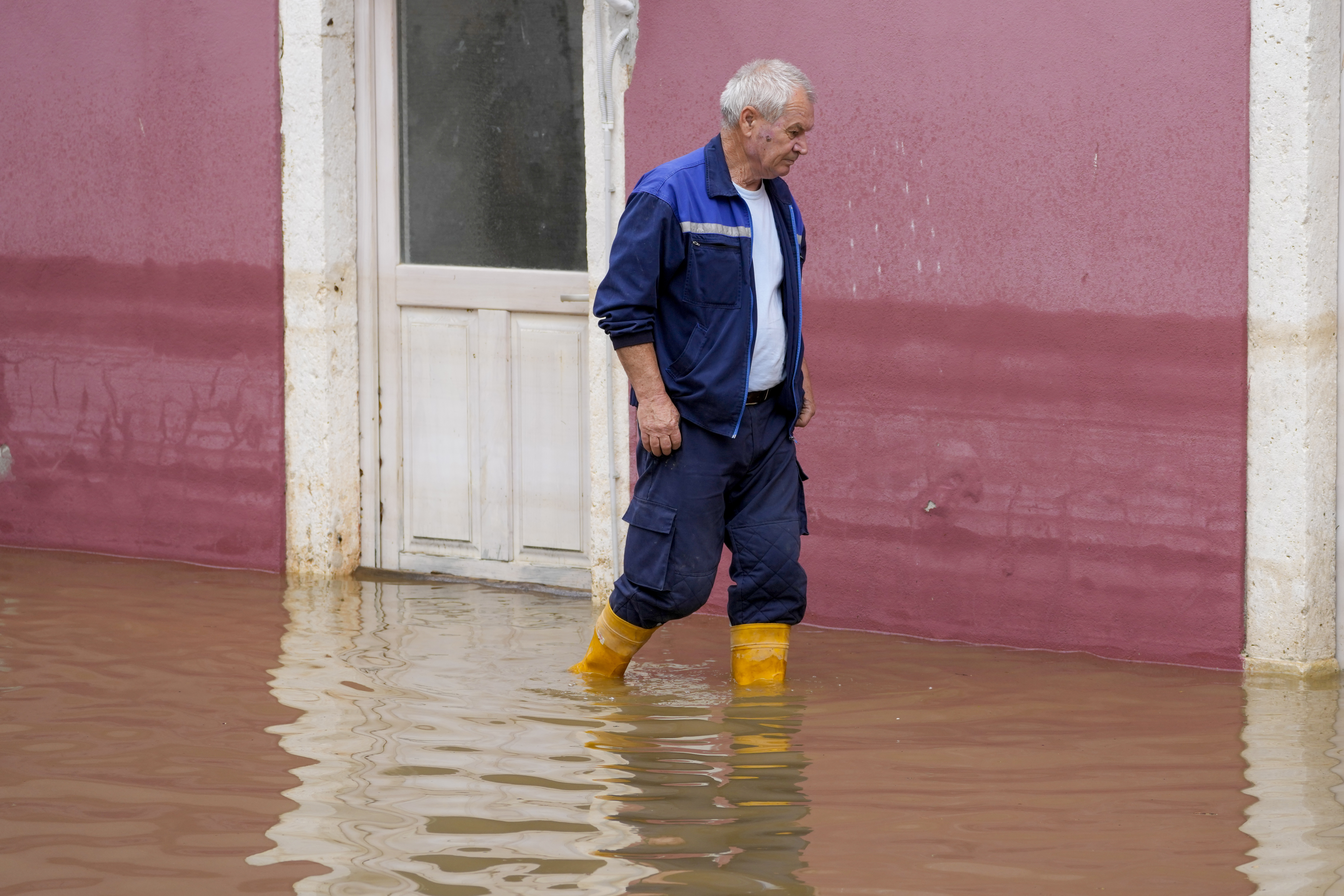A man wades through flooding waters in Obrovac, Croatia, Tuesday, May 16, 2023. 