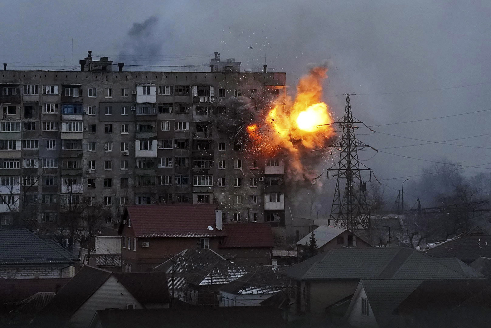 An explosion tears a hole in the side of an apartment building after a Russian tank fired a rocket in Mariupol, Ukraine.