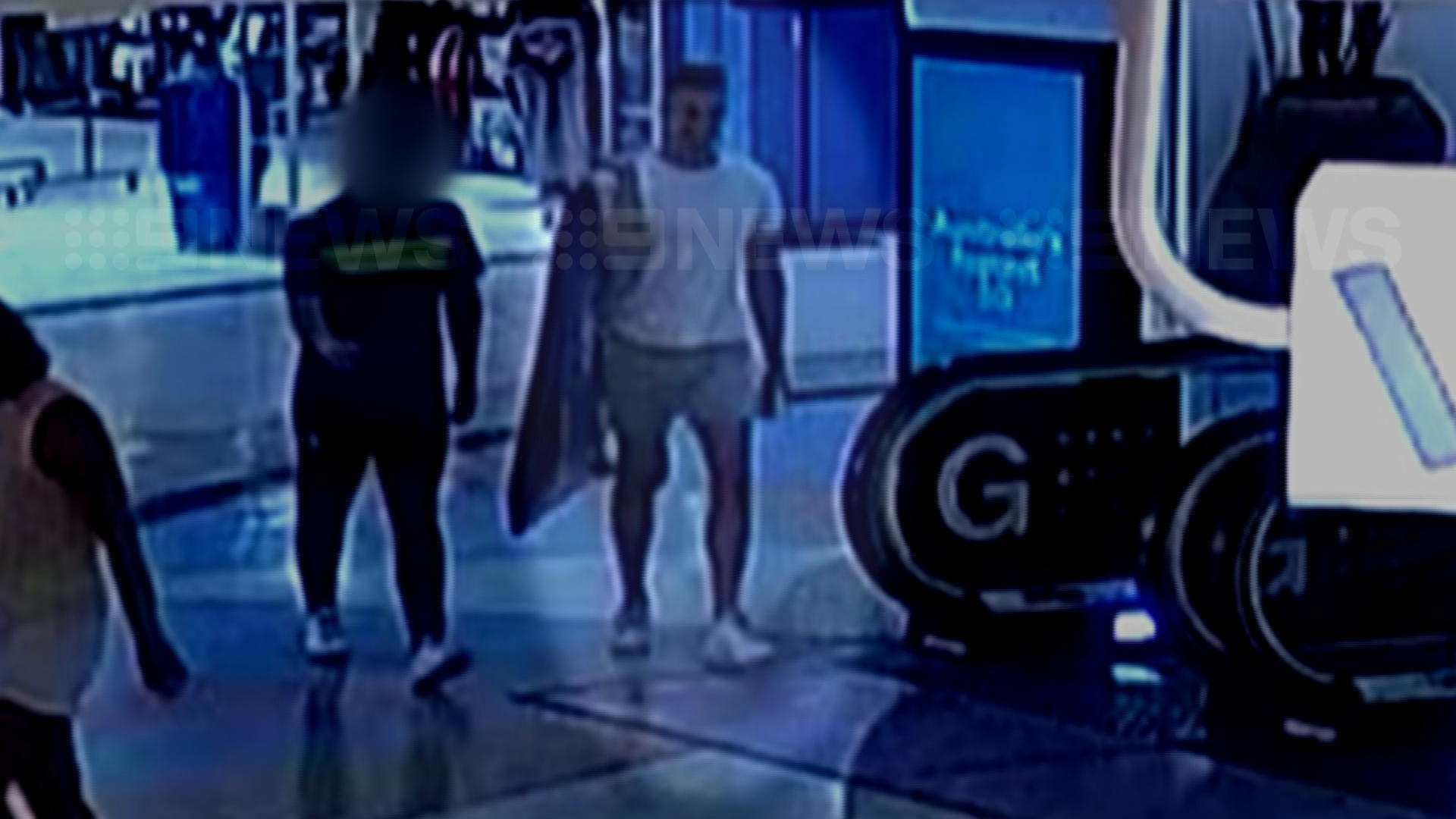 CCTV of Beau Lamarre-Condon and a friend walking out of a shop with a surfboard bag.