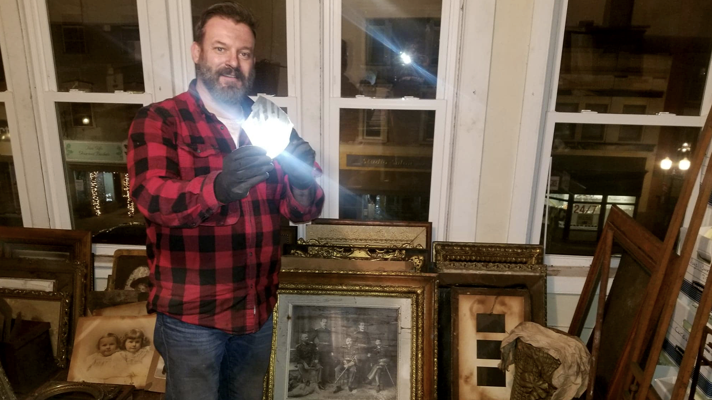 Mr Whitcomb holds a fragment from a glass photographic negative.