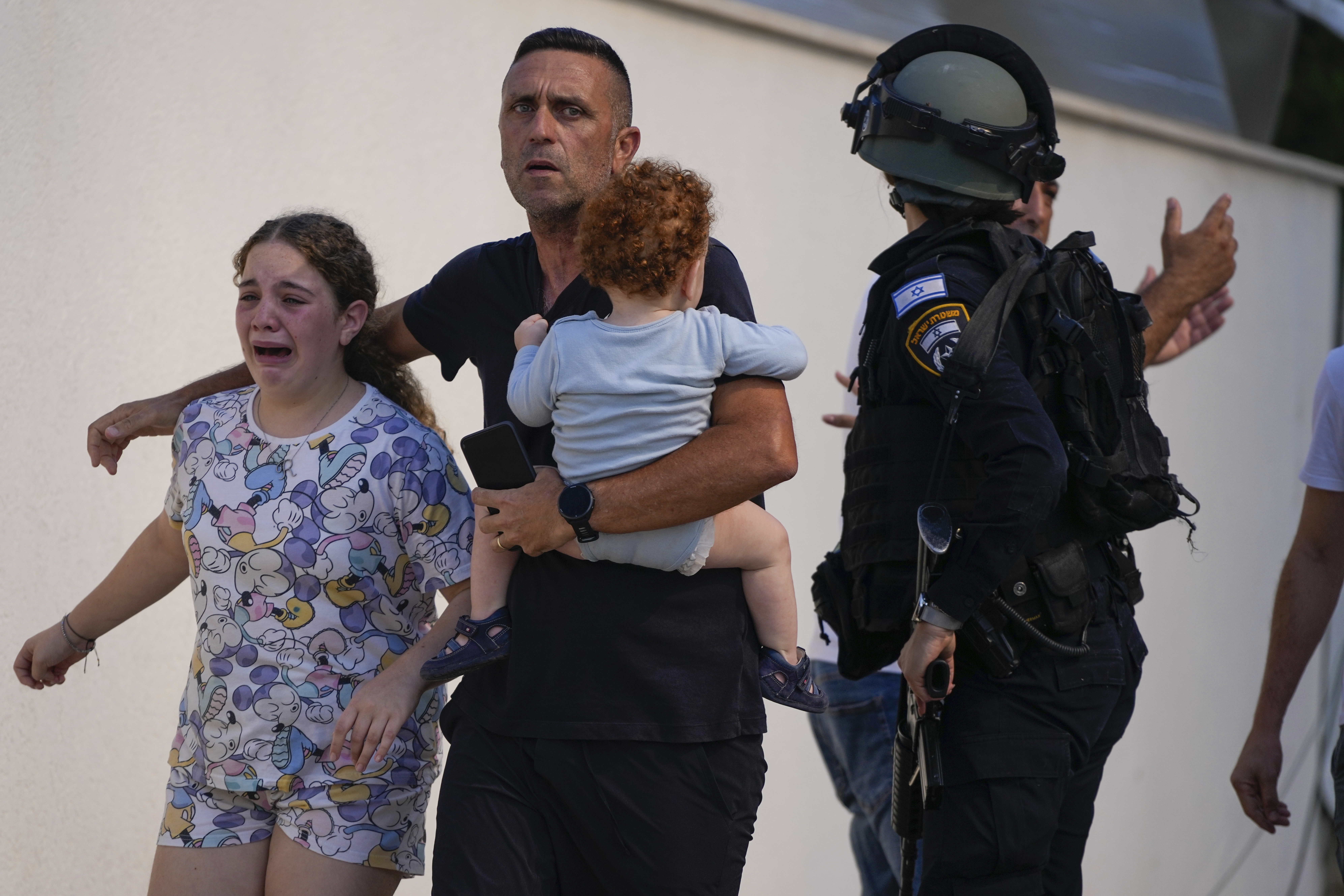 Israeli police officers evacuate a family from a site hit by a rocket fired from the Gaza Strip, in Ashkelon, southern Israel, Saturday, Oct. 7, 2023. 